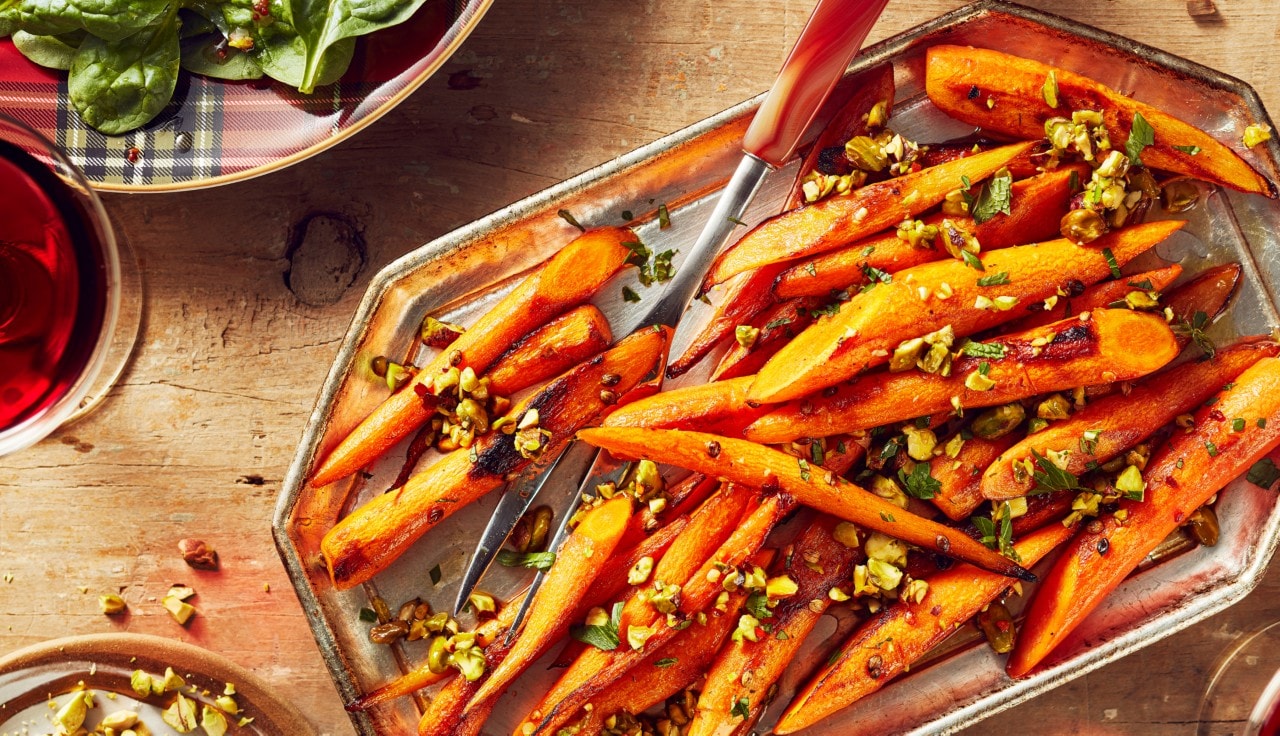Roasted carrots with pistachio topping on a silver platter.