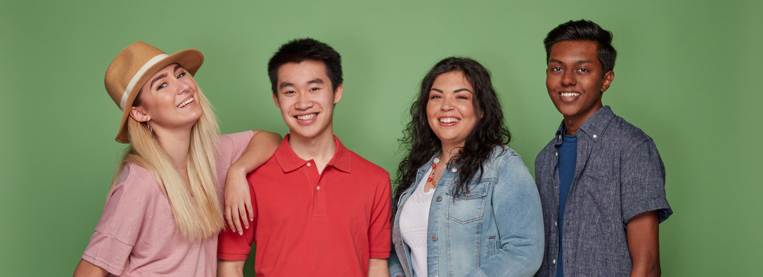 4 young people standing in a row smiling.