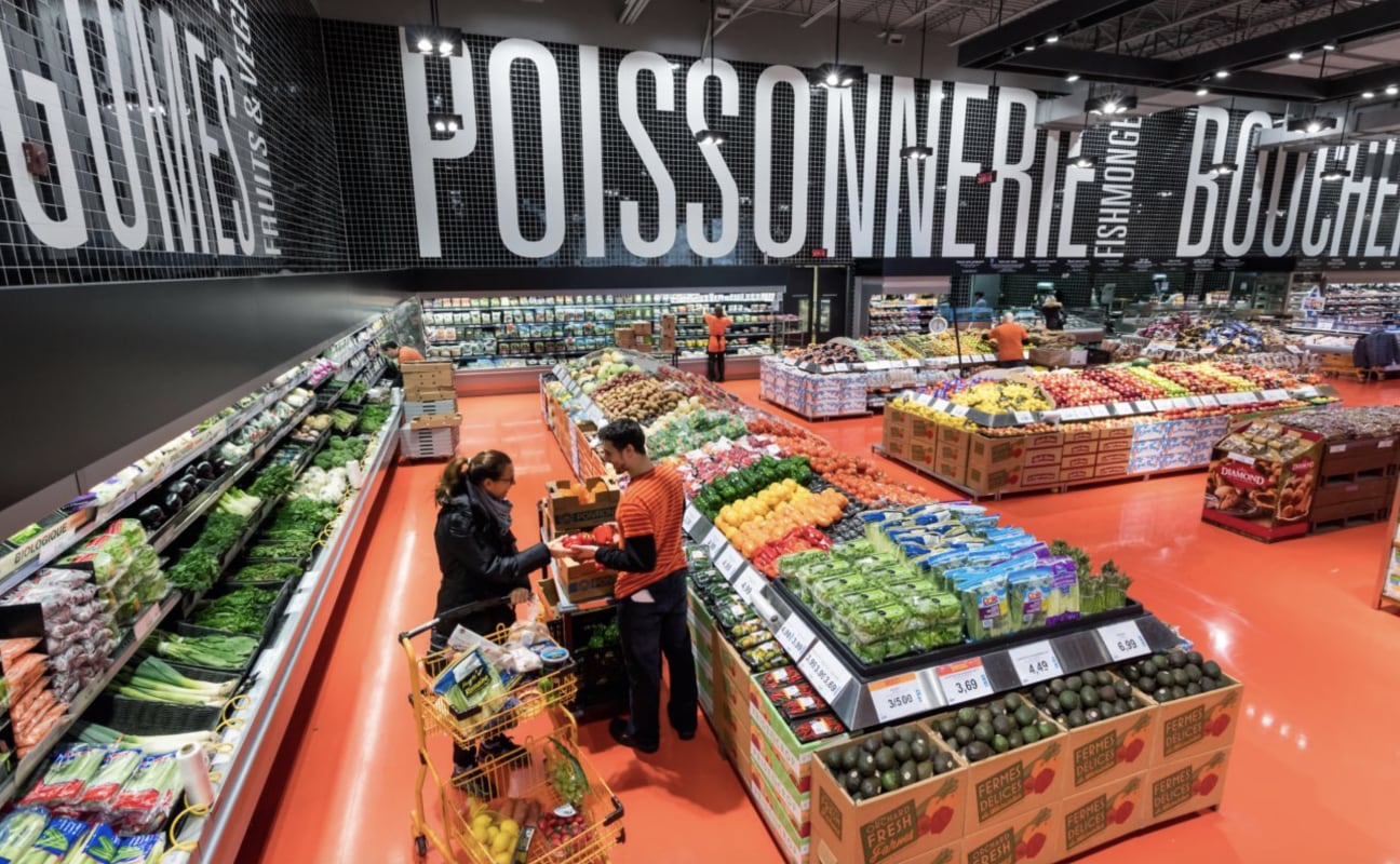 View of employee helping shopper in the produce section of grocery store.