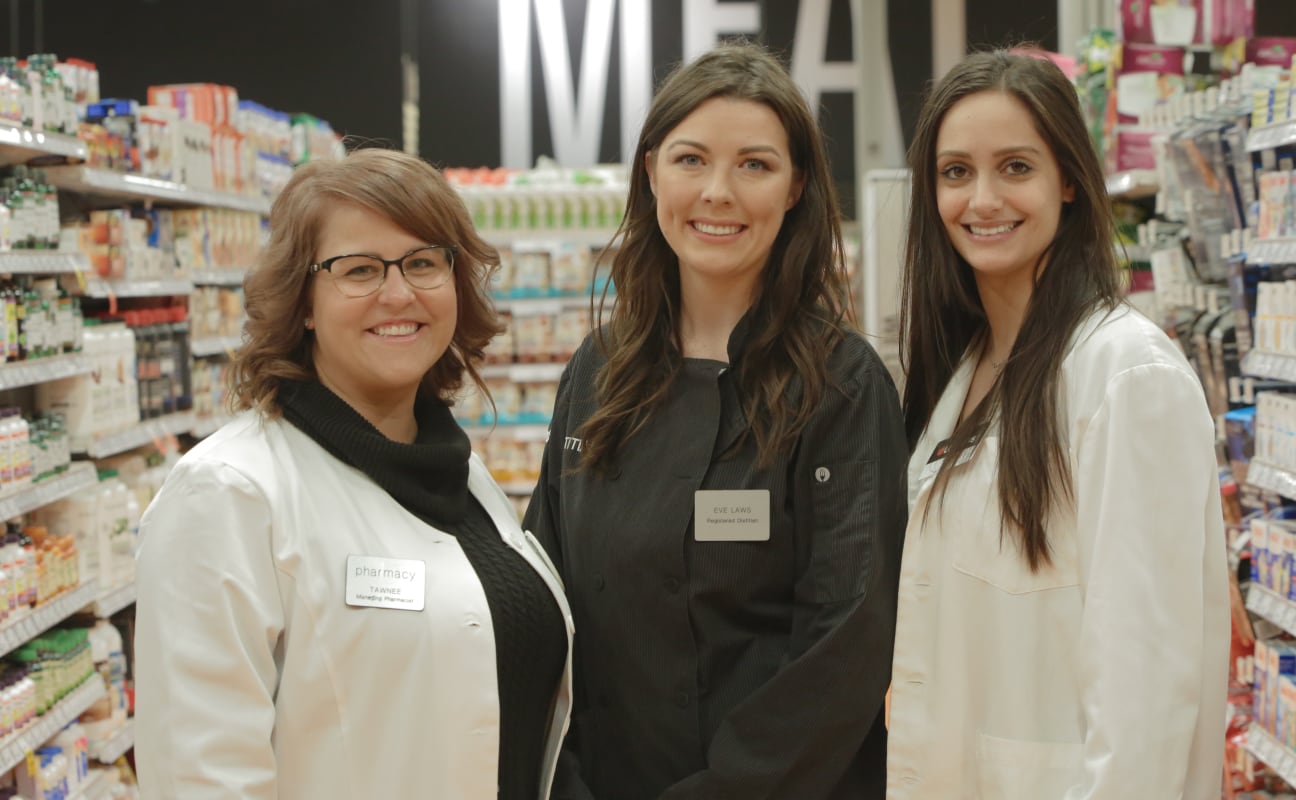 Three healthcare employees smiling with white coats. 