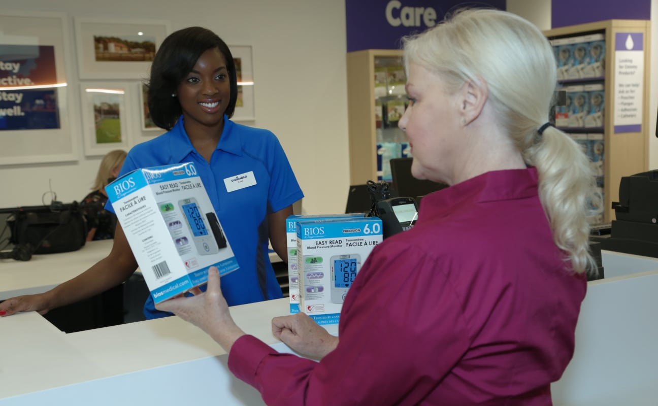 Smiling healthcare worker behind a desk helping a customer with products. 