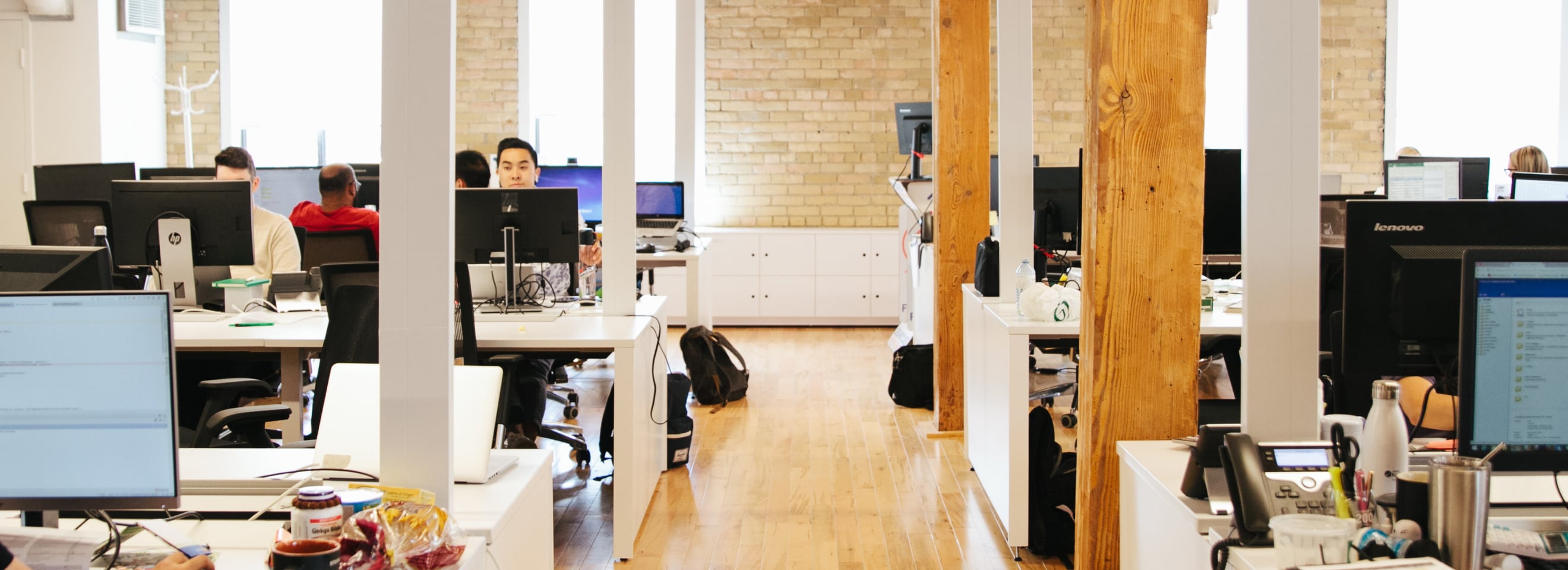 People working in loft-style open concept office with wooden beams. 