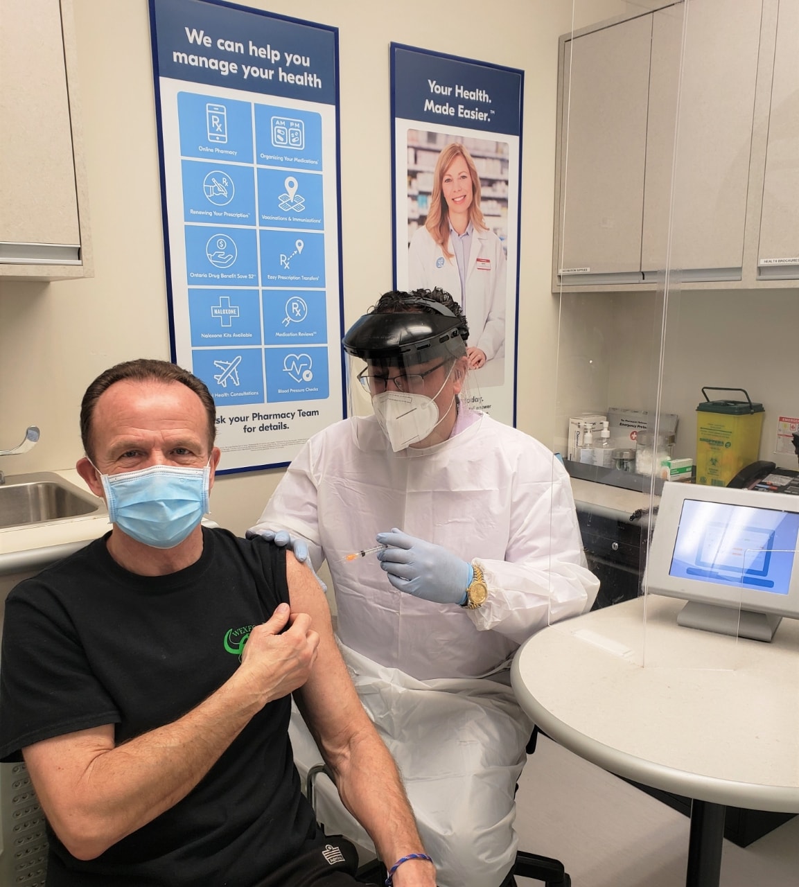 Shoppers Drug Mart Associate Owner John Papastergiou gives the store’s first COVID-19 vaccine to John Stavropoulos in Toronto, ON