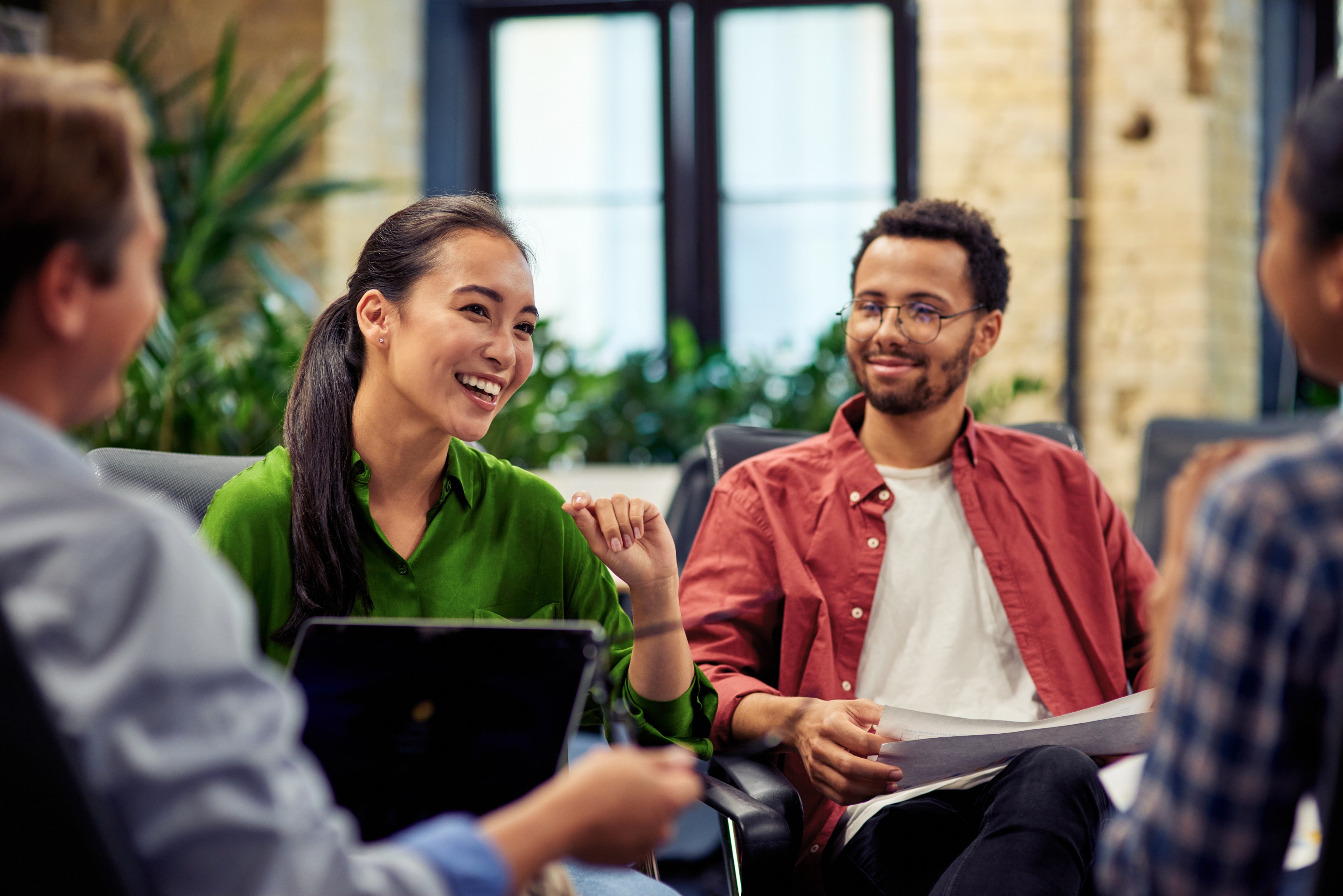 A male employee looks attentively at a smiling female employee. There are two other employees in front of them.