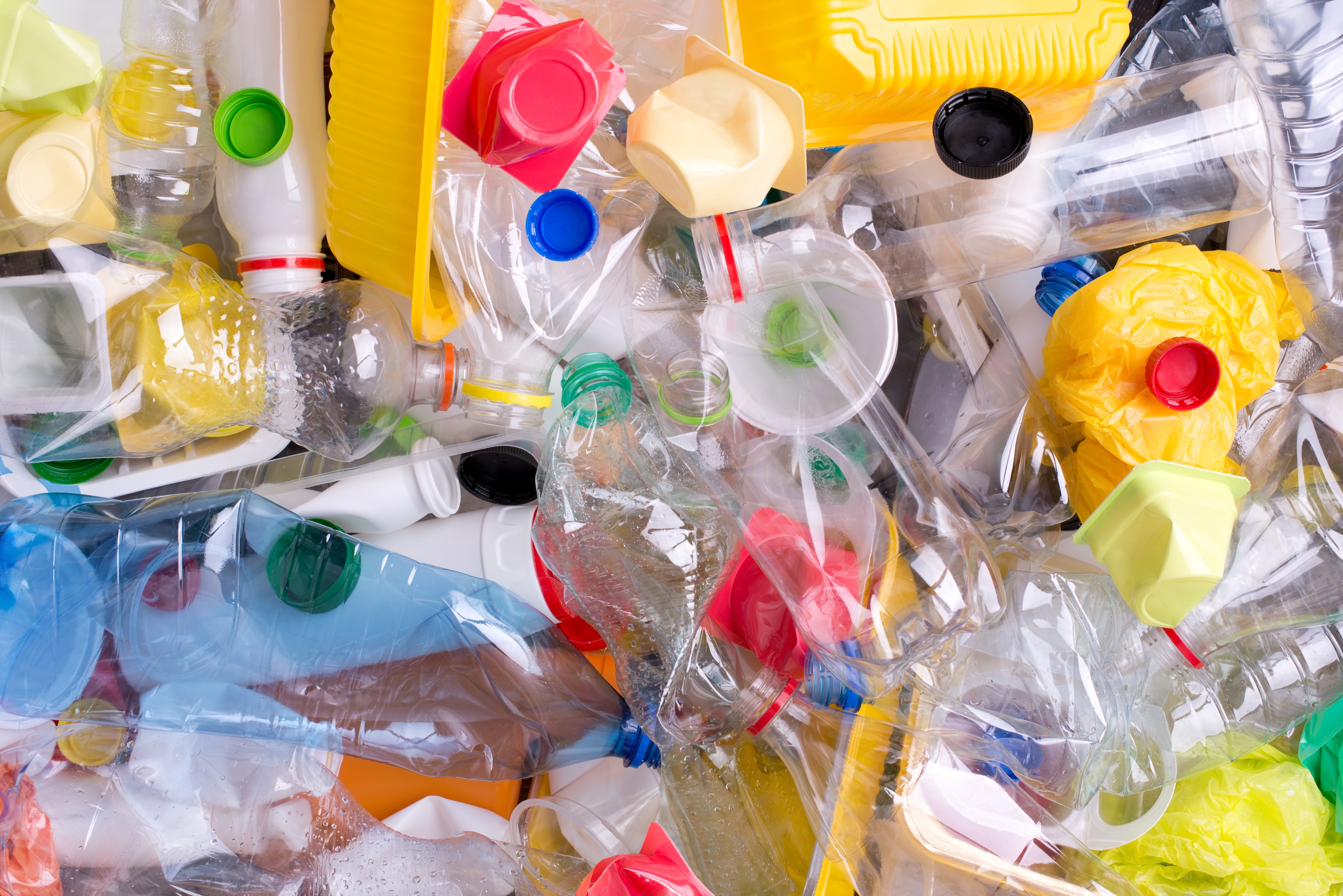 An assortment of plastic waste, including bottles, bags, and containers, is piling up.
