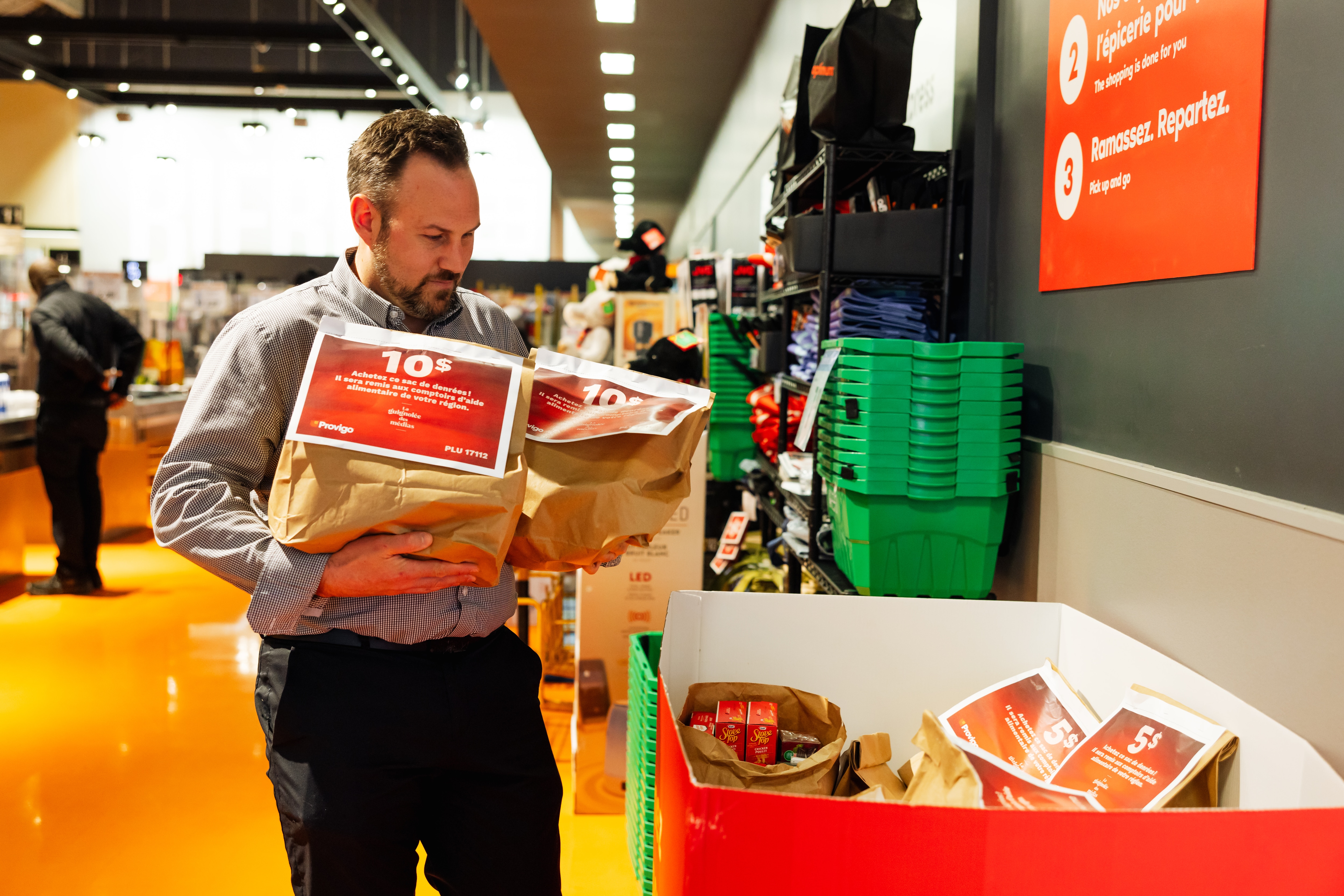 A Loblaws customer happily places two bags of food into a donation bin.