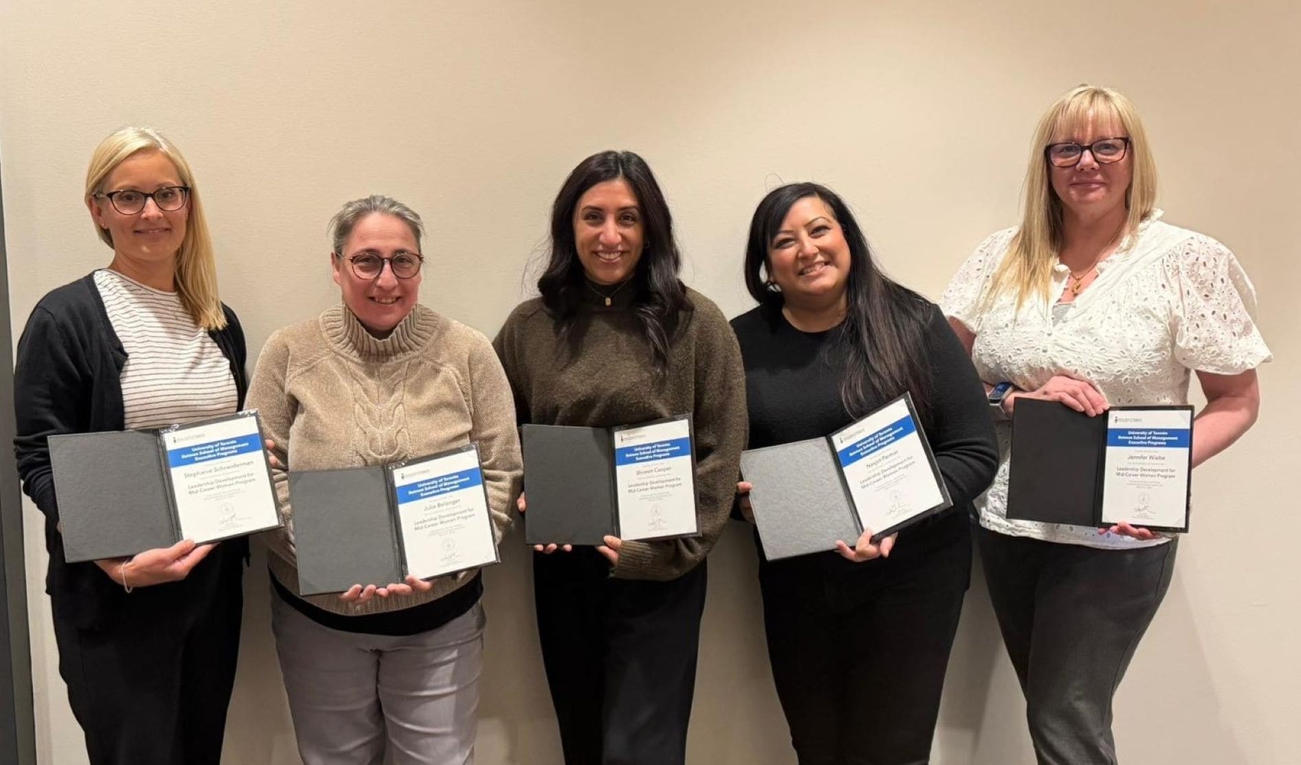 Julie Bélanger and four fellow graduates from the Rotman School of Management holding their completion certificates. 