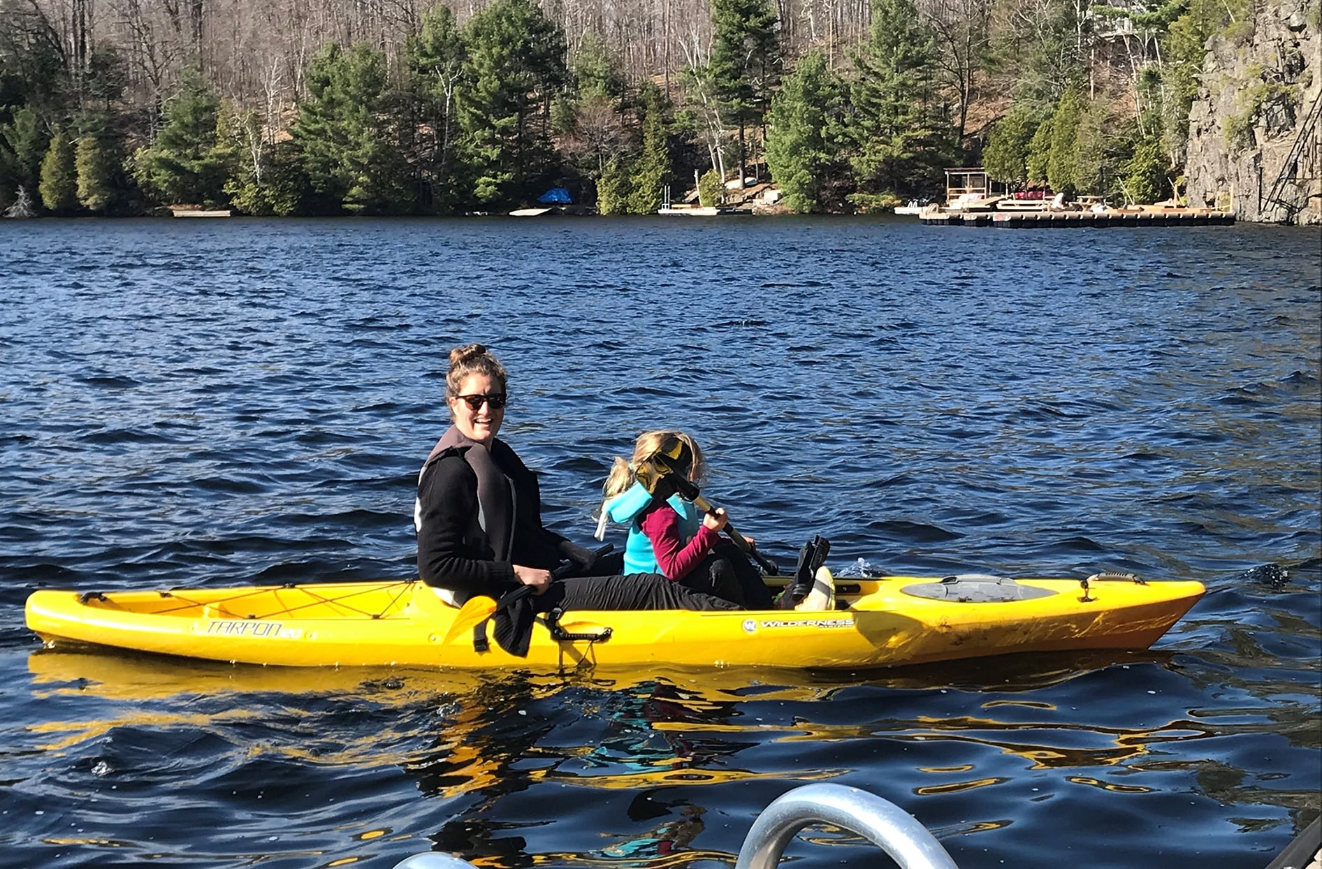 Alana sits in a kayak with her daughter in the lake. 