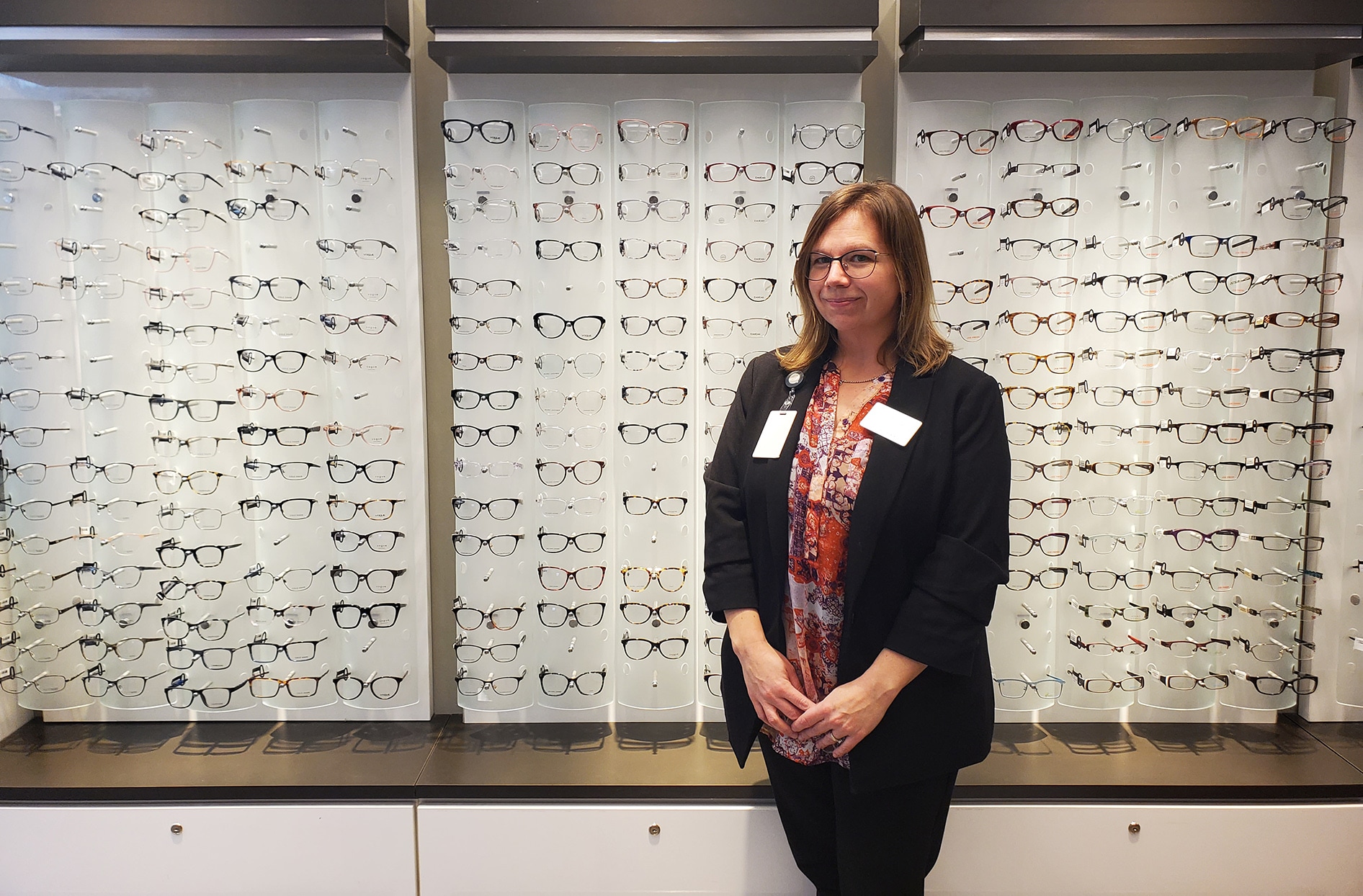 Alia stands inside her store in front of a display of prescription glasses.  