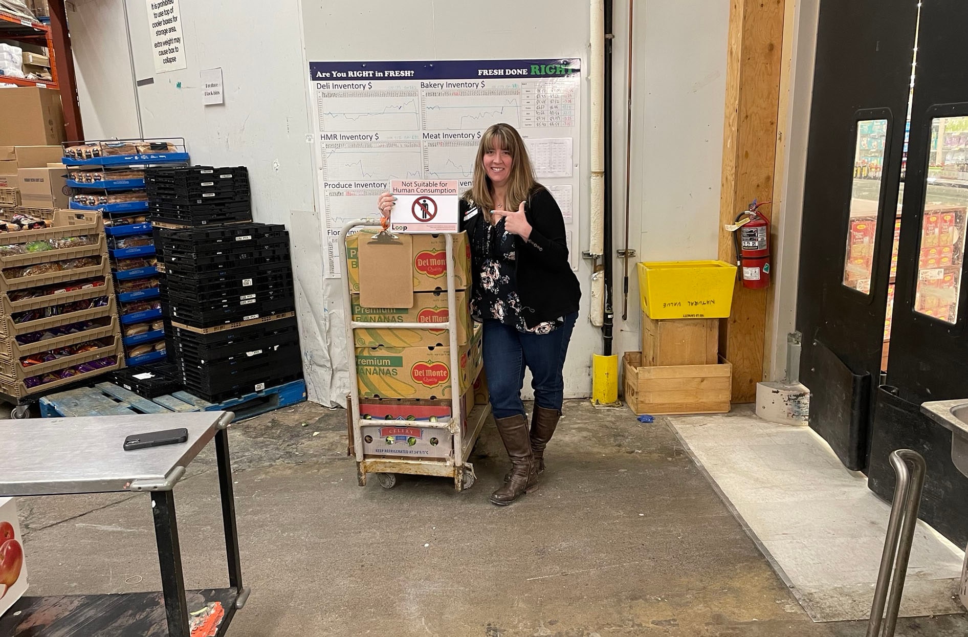 Bev stands next to several crates with a sign that says “Not suitable for human consumption”. 
