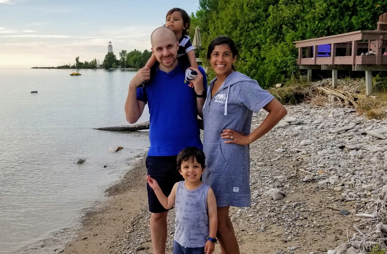 Man with baby on shoulders standing next to woman and toddler