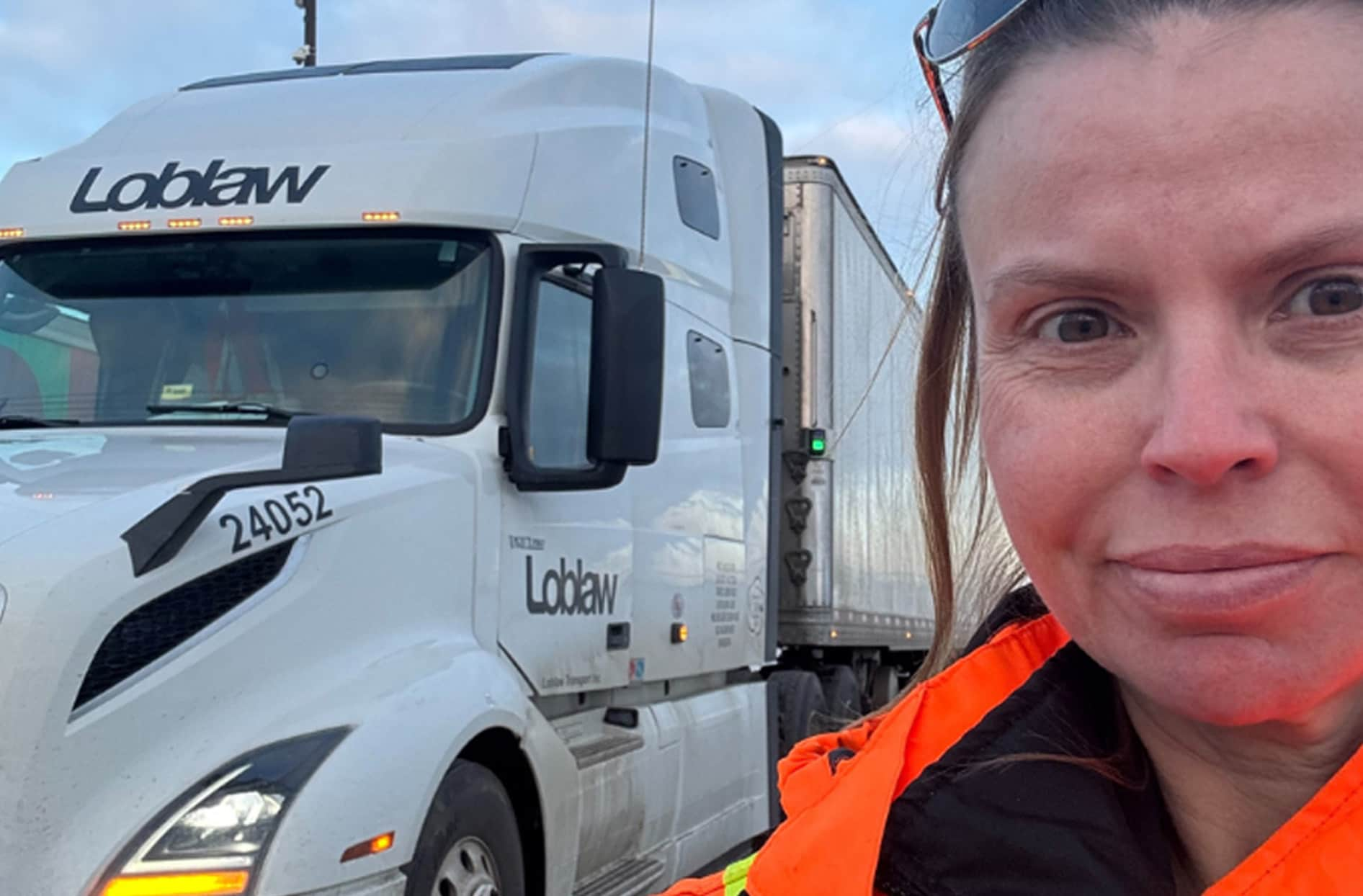 Cara stands in front of her truck smiling. 