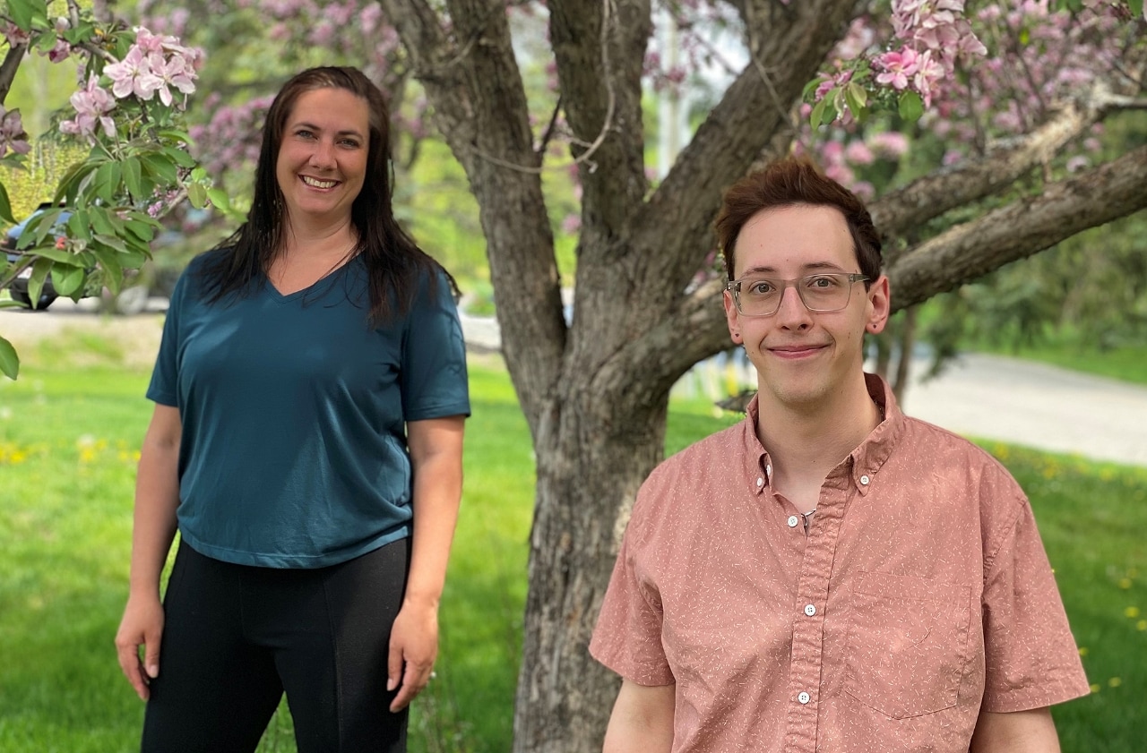 Catherine and Kyle standing underneath cherry blossom trees