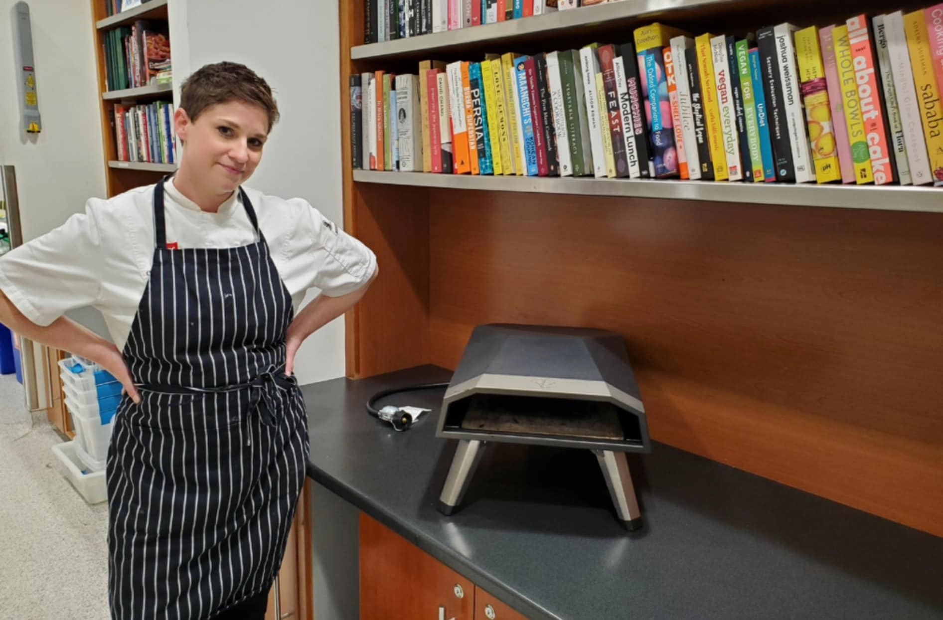 Charmaine se tient à côté du four à pizza PC dans la cuisine-laboratoire du siège social.  