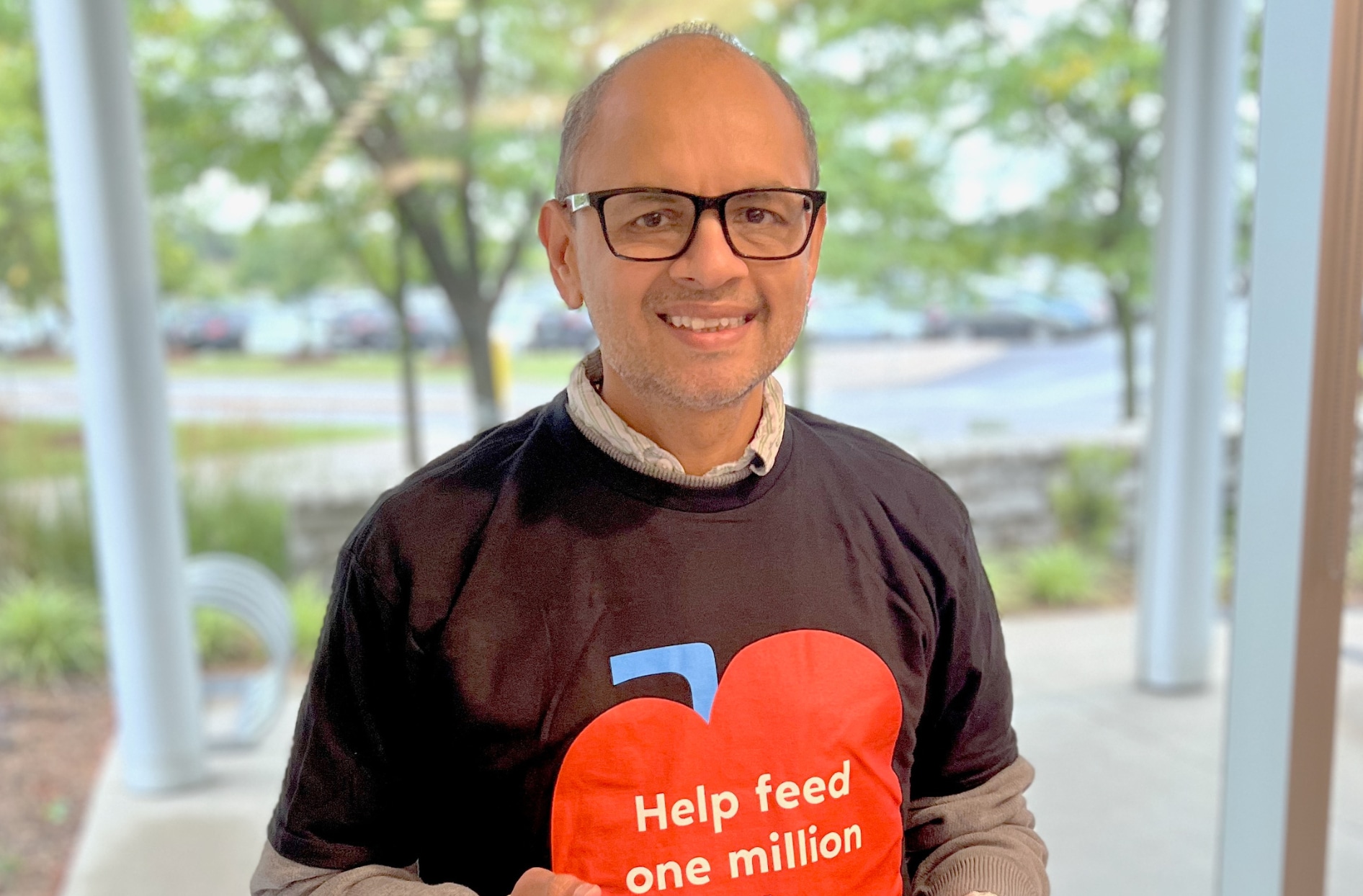 A photo of Dipak standing and smiling while wearing a President’s Choice Children’s Charity t-shirt. 