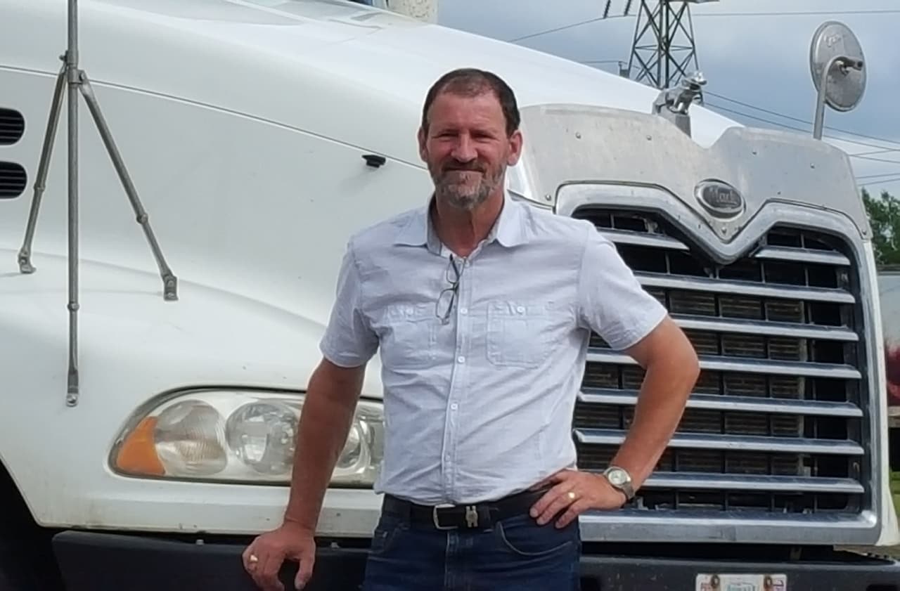 Edgar stands in front of a truck smiling