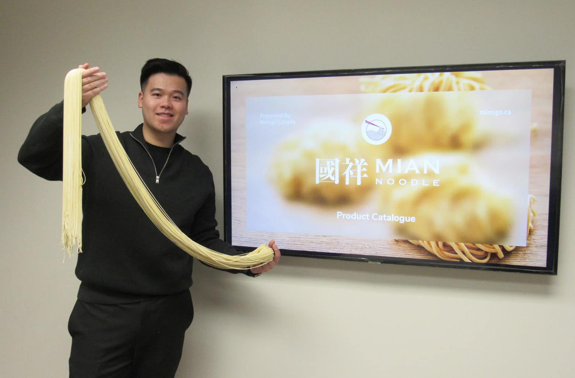 Mimigo president, Kerry Tam poses proudly holding freshly handcrafted noodles at the Mimigo office. 
