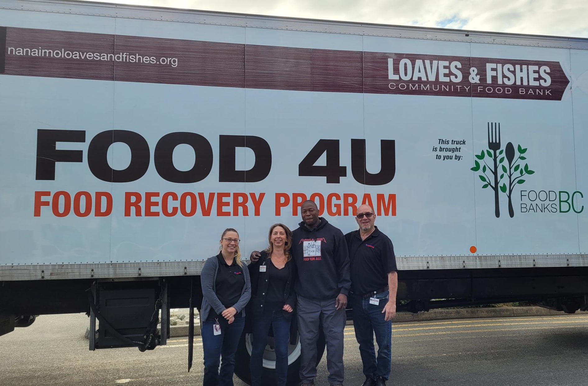 Greg se tient devant le camion de la banque alimentaire communautaire Loaves and Fishes avec quelques-uns de ses membres. 