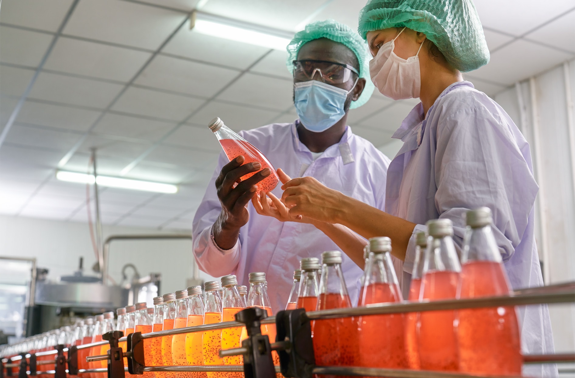 Factory workers examining a beverage on the product manufacturing line.