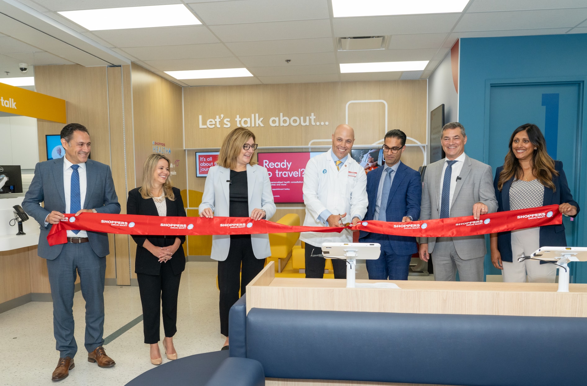 Fabio et d’autres membres de l’équipe de Shoppers Drug Mart sont debout à l’intérieur de la clinique de Burlington et coupent un ruban rouge. 