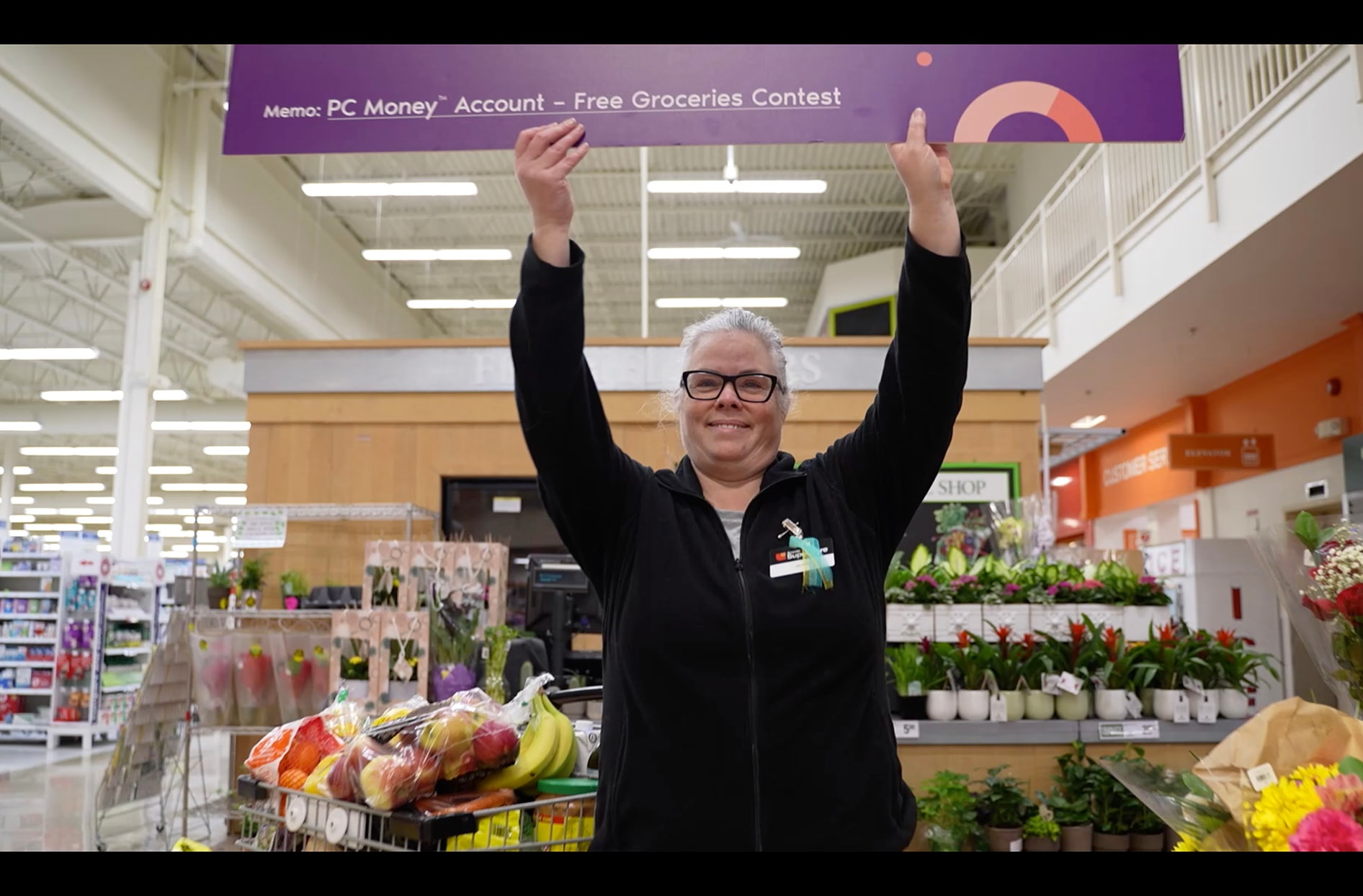 Jackie stands in the store holding her free groceries for a year cheque. 
