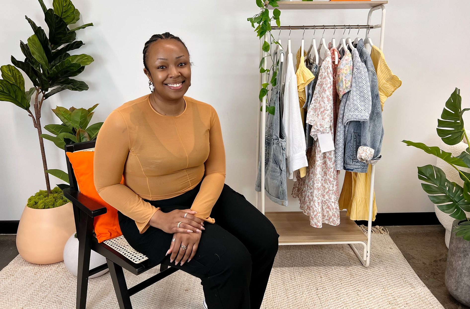 Jade se trouve à l’intérieur du bureau Joe Fresh avec des pièces de la collection derrière elle.  