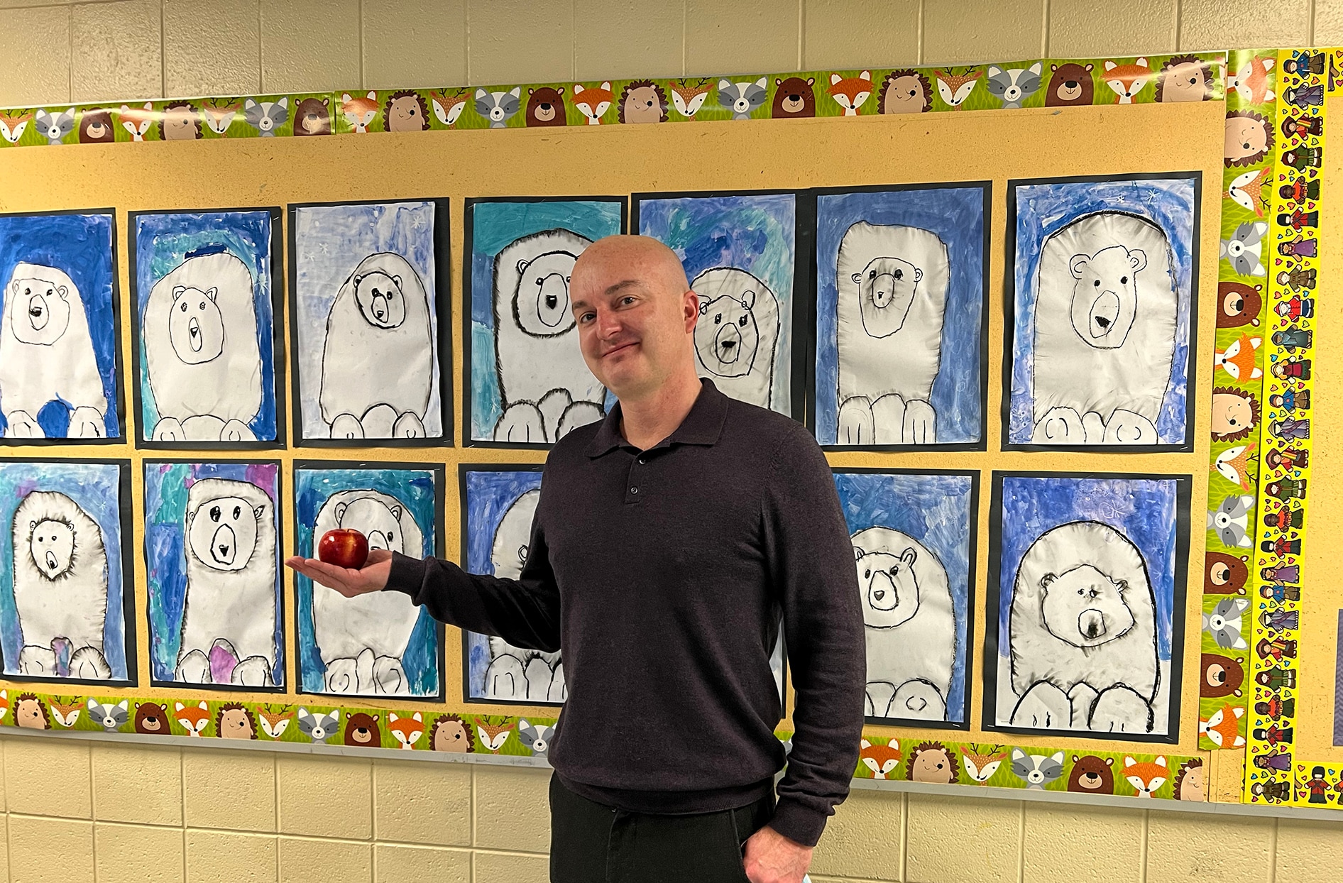 Jay stands in his school holding an apple