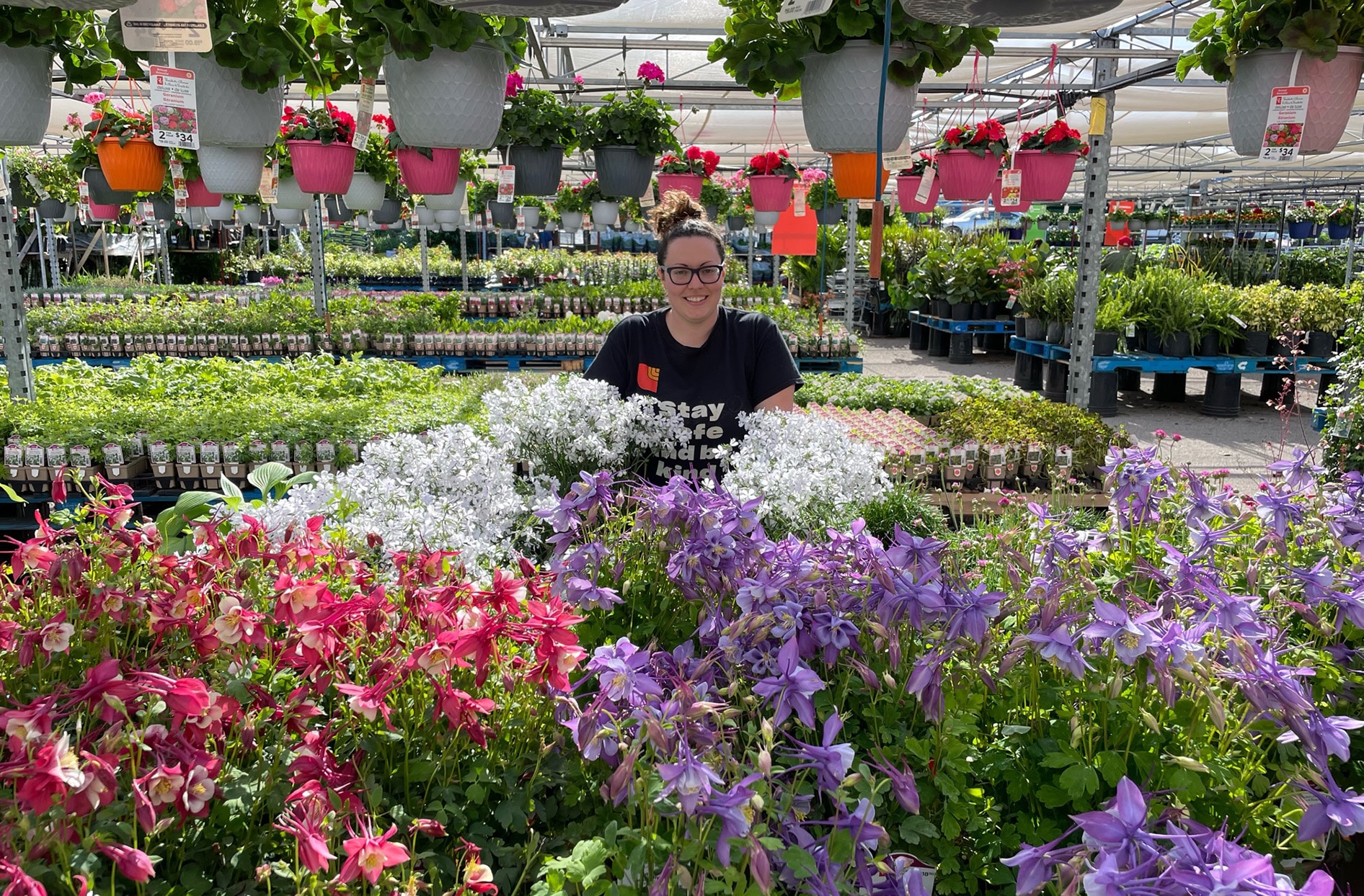 Jennifer est assise derrière un étalage de différentes fleurs et plantes dans la jardinerie de Loblaws.