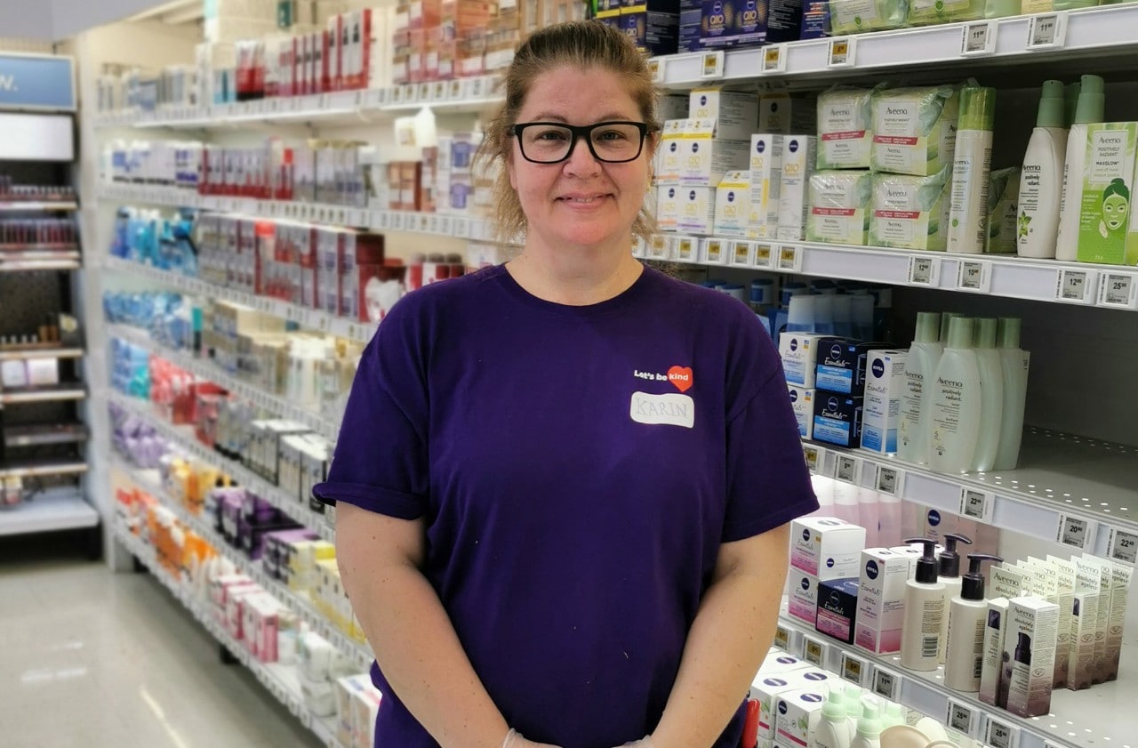 Karen debout dans une allée de santé et de beauté dans son magasin