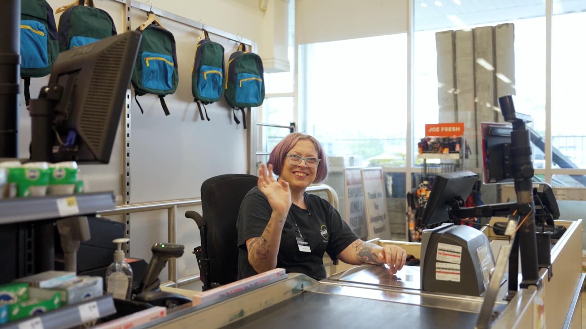 Tina smiles and waves from her accessible checkout at Hansen’s Your Independent Grocer.