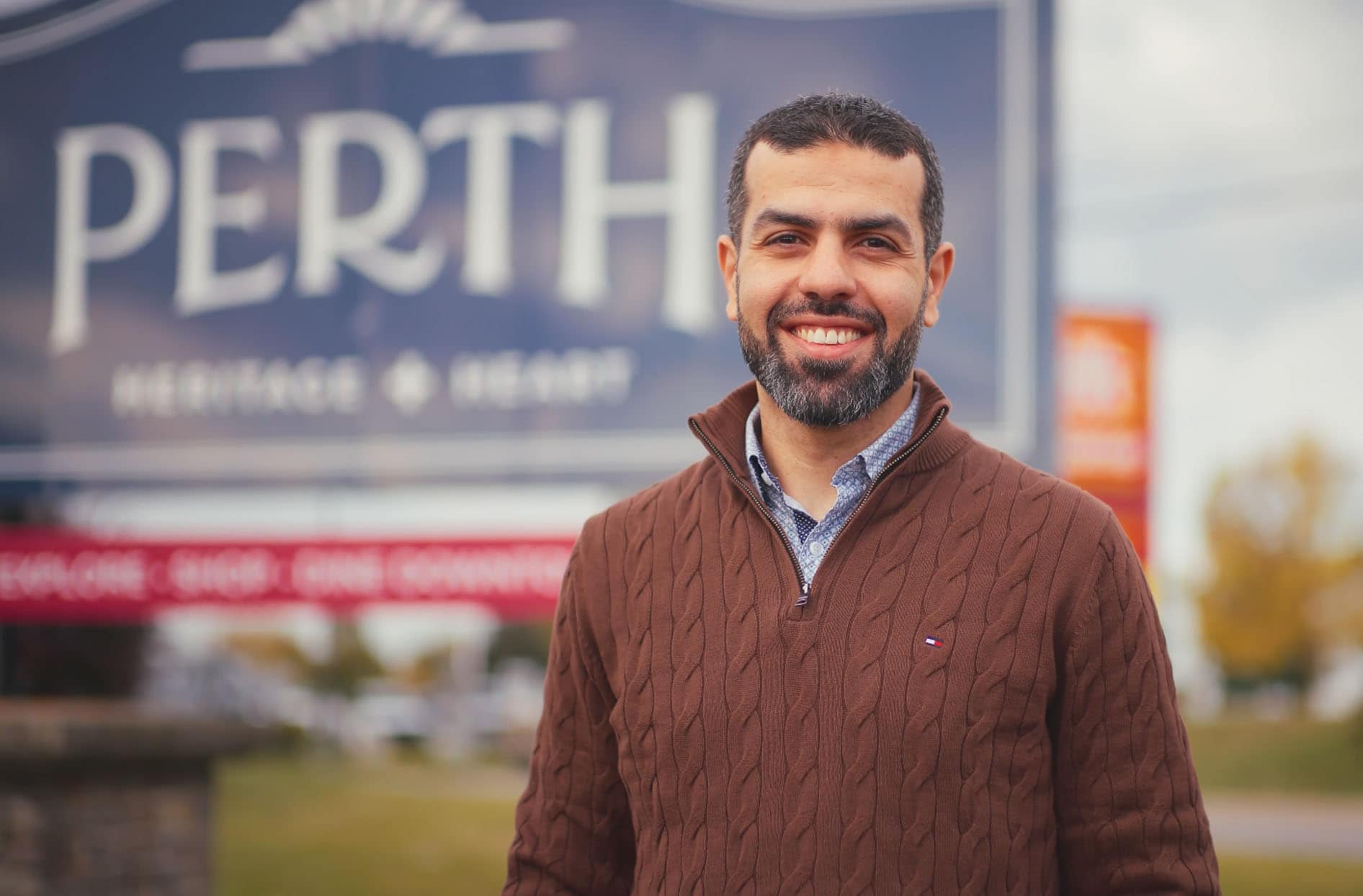 Shoppers Drug Mart Associate-Owner Khaled Youssef posing proudly in front of the Perth sign in his community. 