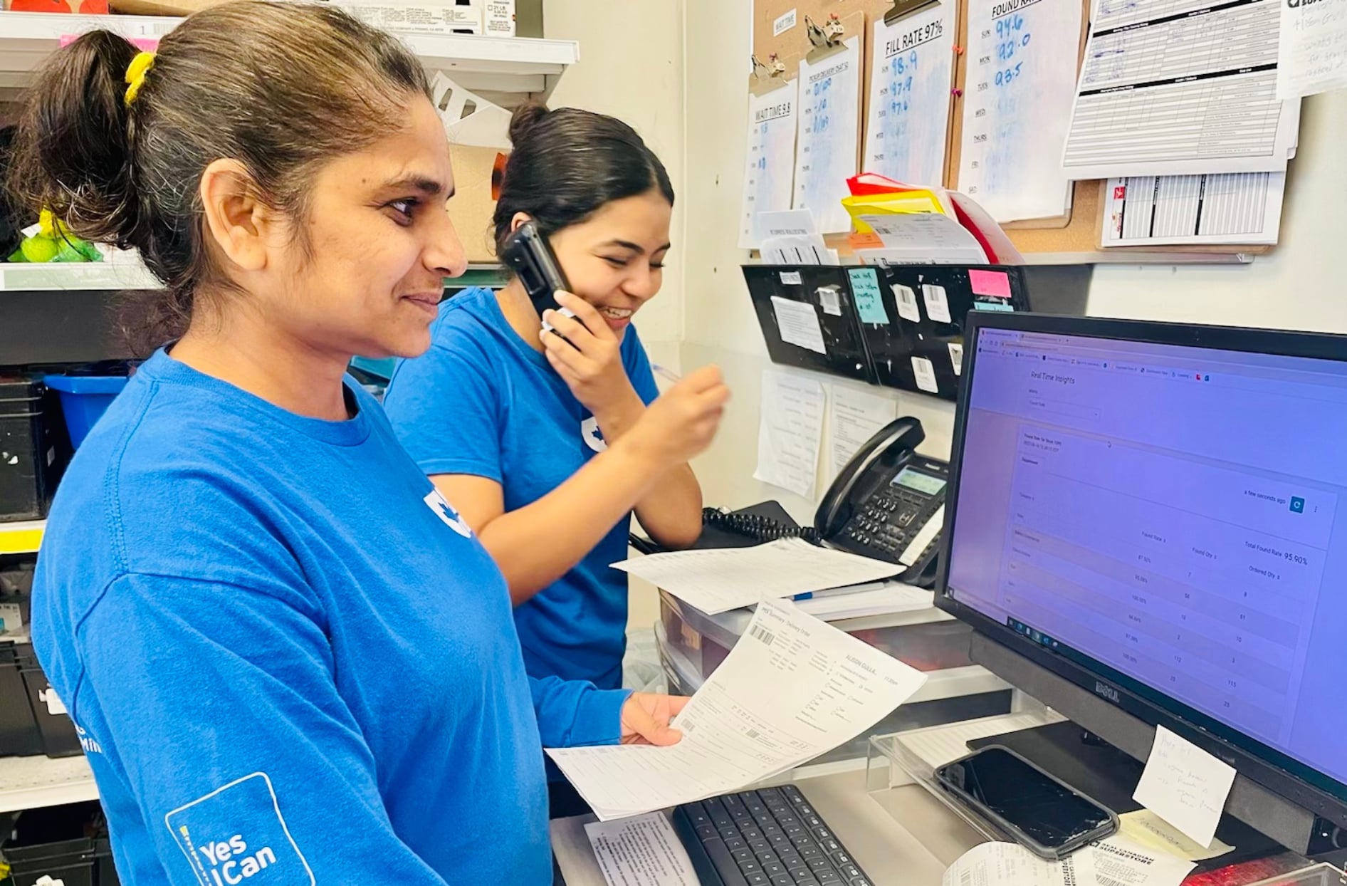 A photo of two colleagues from a Real Canadian Superstore managing orders on the computer inside their store. 