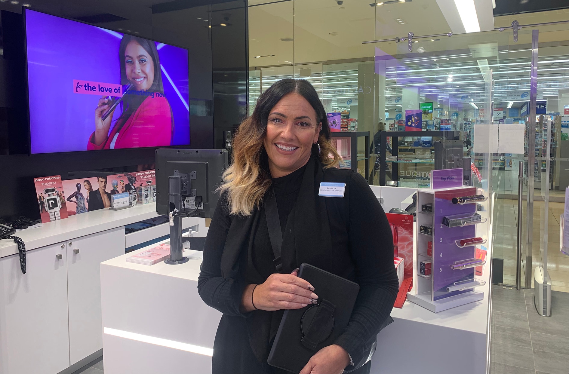 Rayelyn tient une tablette alors qu’elle se tient devant un bureau de présentation dans un Shoppers Drug Mart.