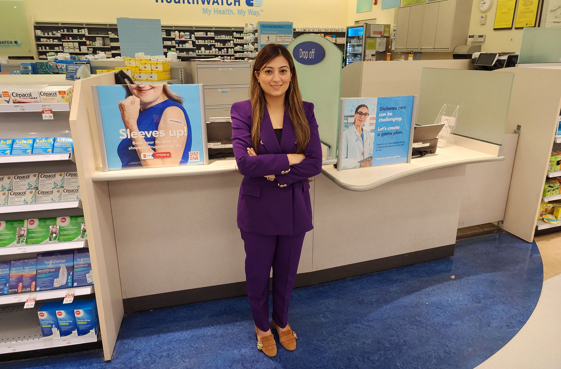 Ruchi stands in front of the pharmacy at a Shoppers Drug Mart location. 