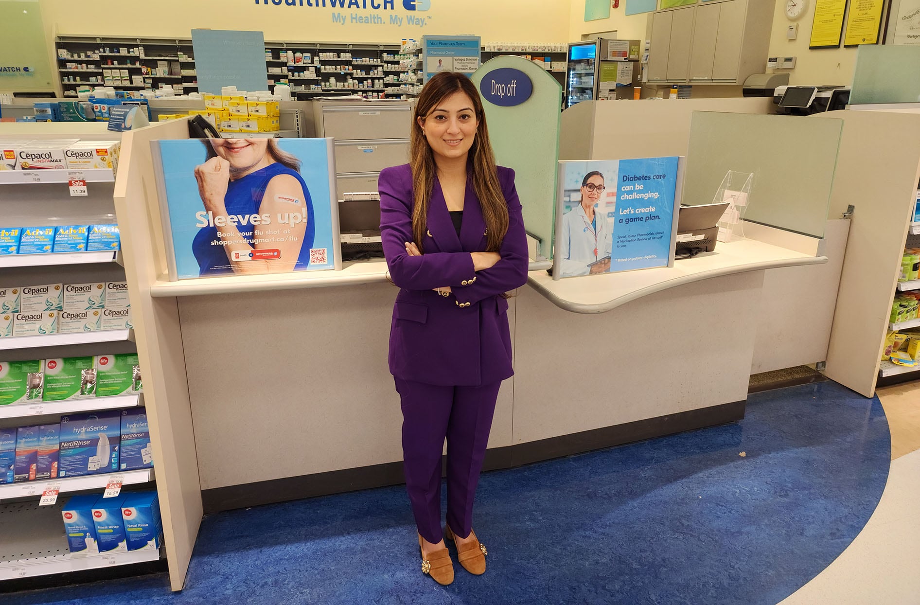 Ruchi se trouve devant le comptoir de la pharmacie dans un magasin Shoppers Drug Mart.