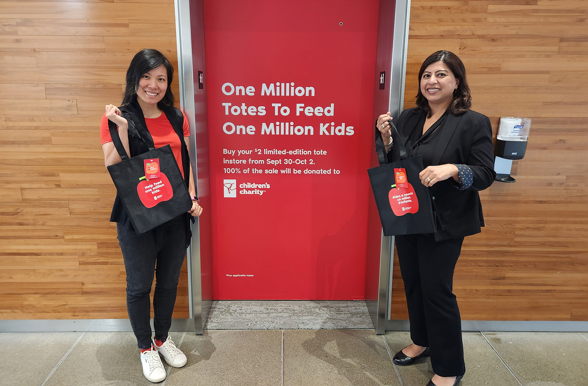 Shahla and Rebecca stand in front of an elevator at the Loblaw head office holding the tote bags in their hands. 