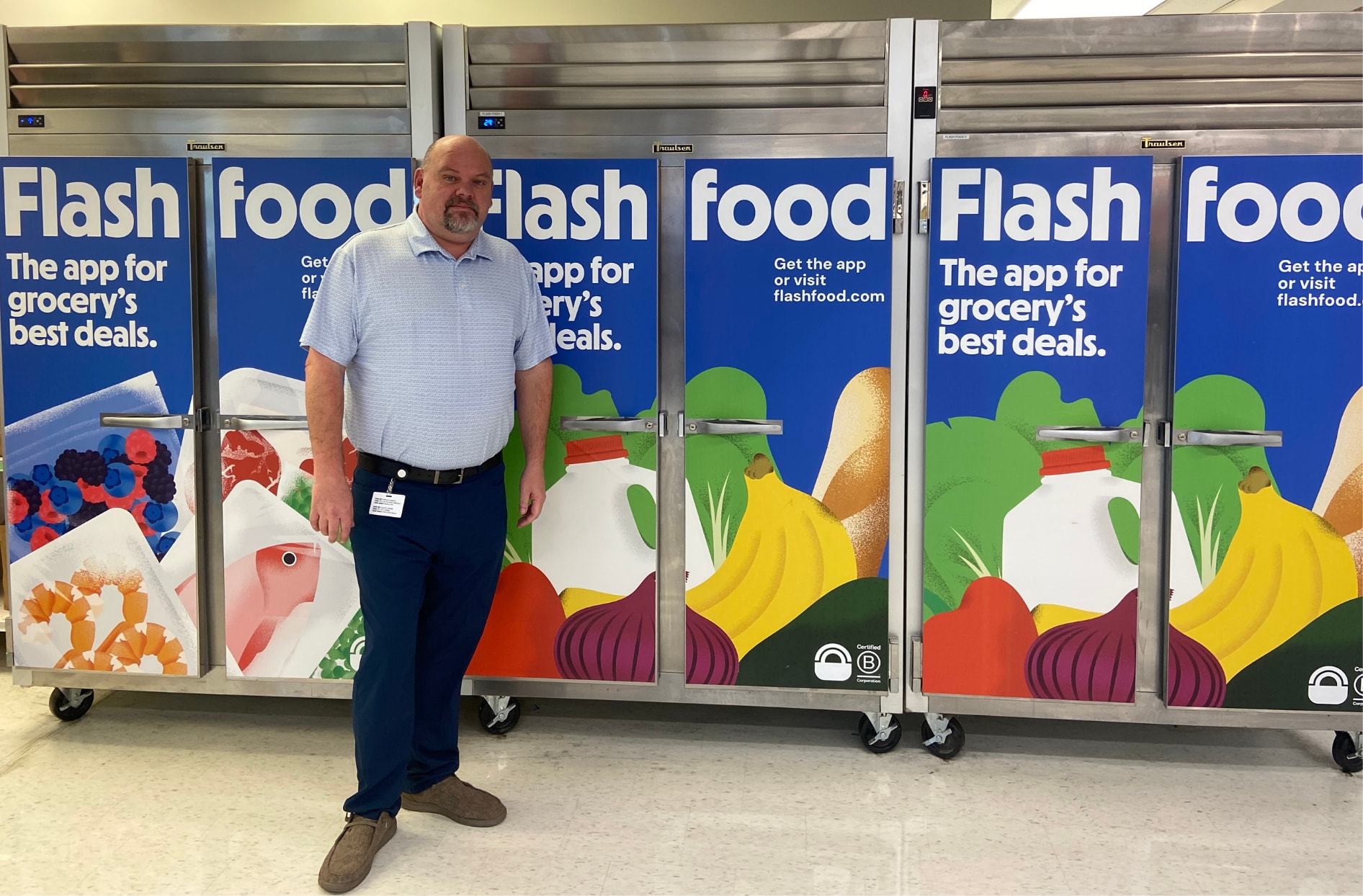 Stacey stands in front of the Flashfood refrigerators inside his store. 