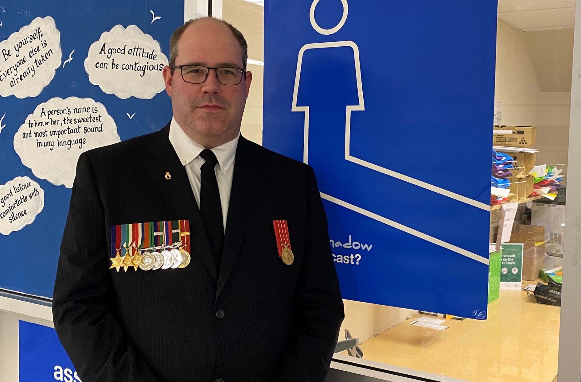 Todd stands in his store wearing his Canada’s Reserve Force uniform showing his medals.