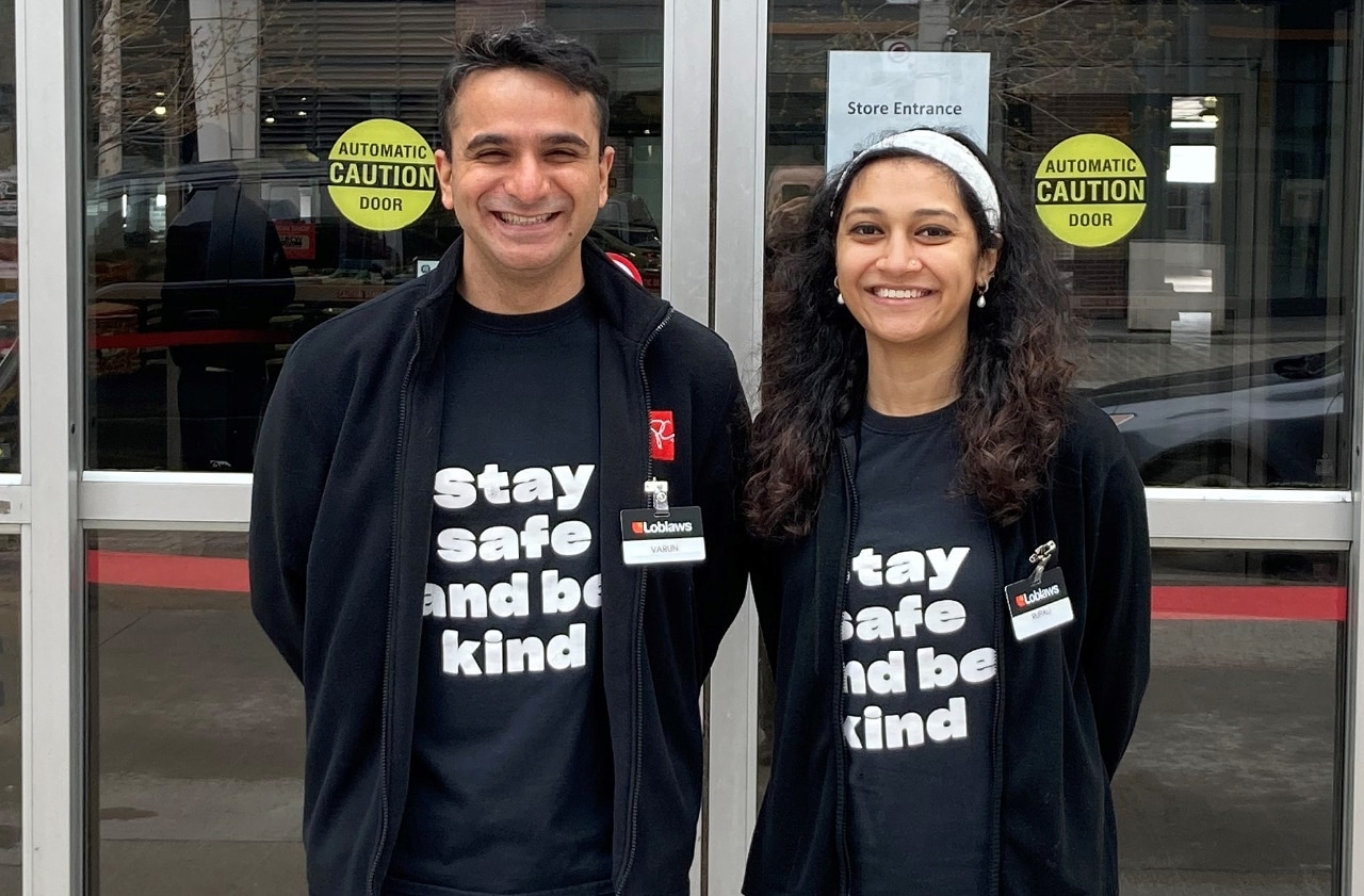 Un homme et une femme souriants se tenant devant une épicerie