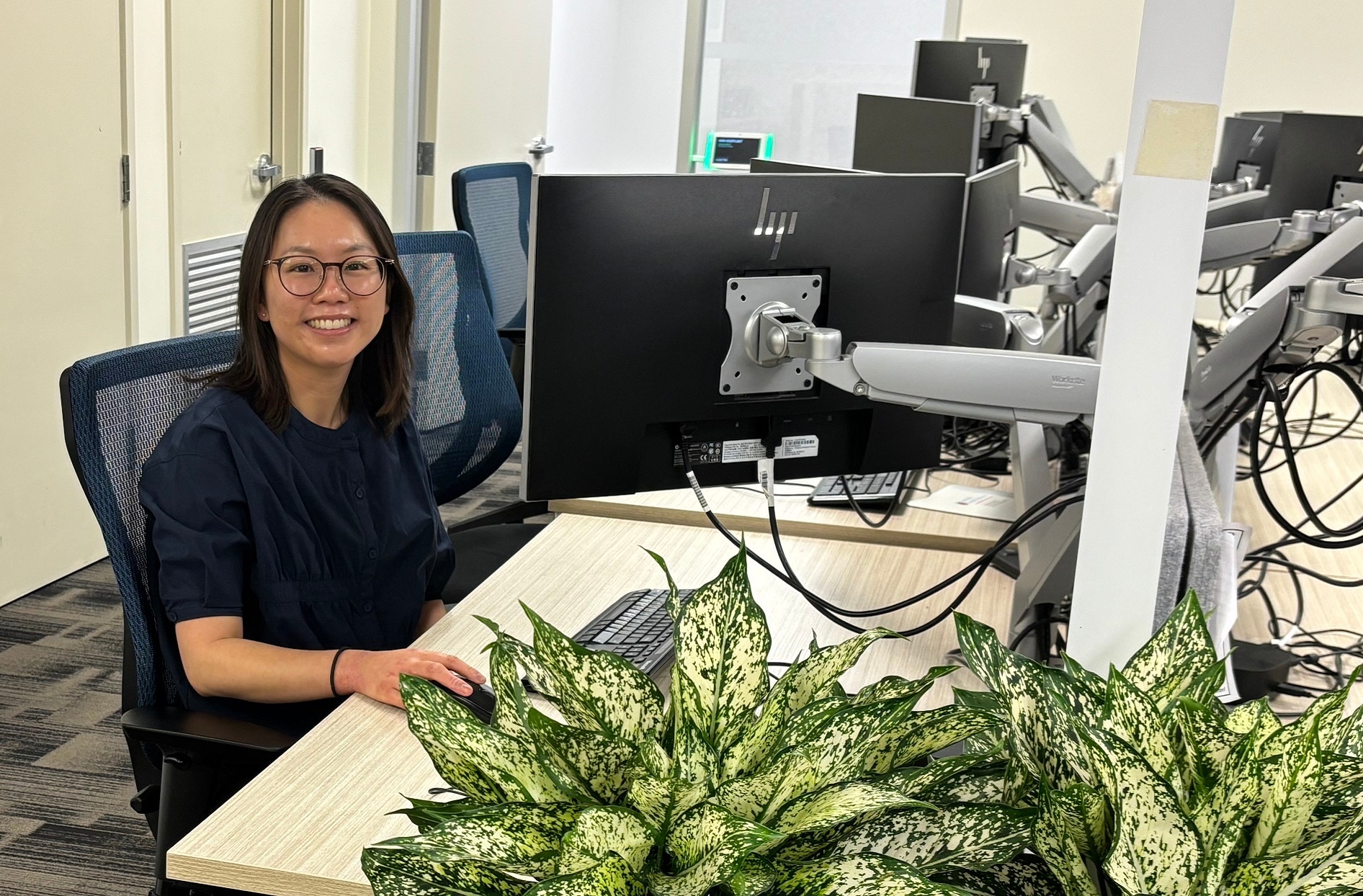 Wendy sits at her desk smiling up. 