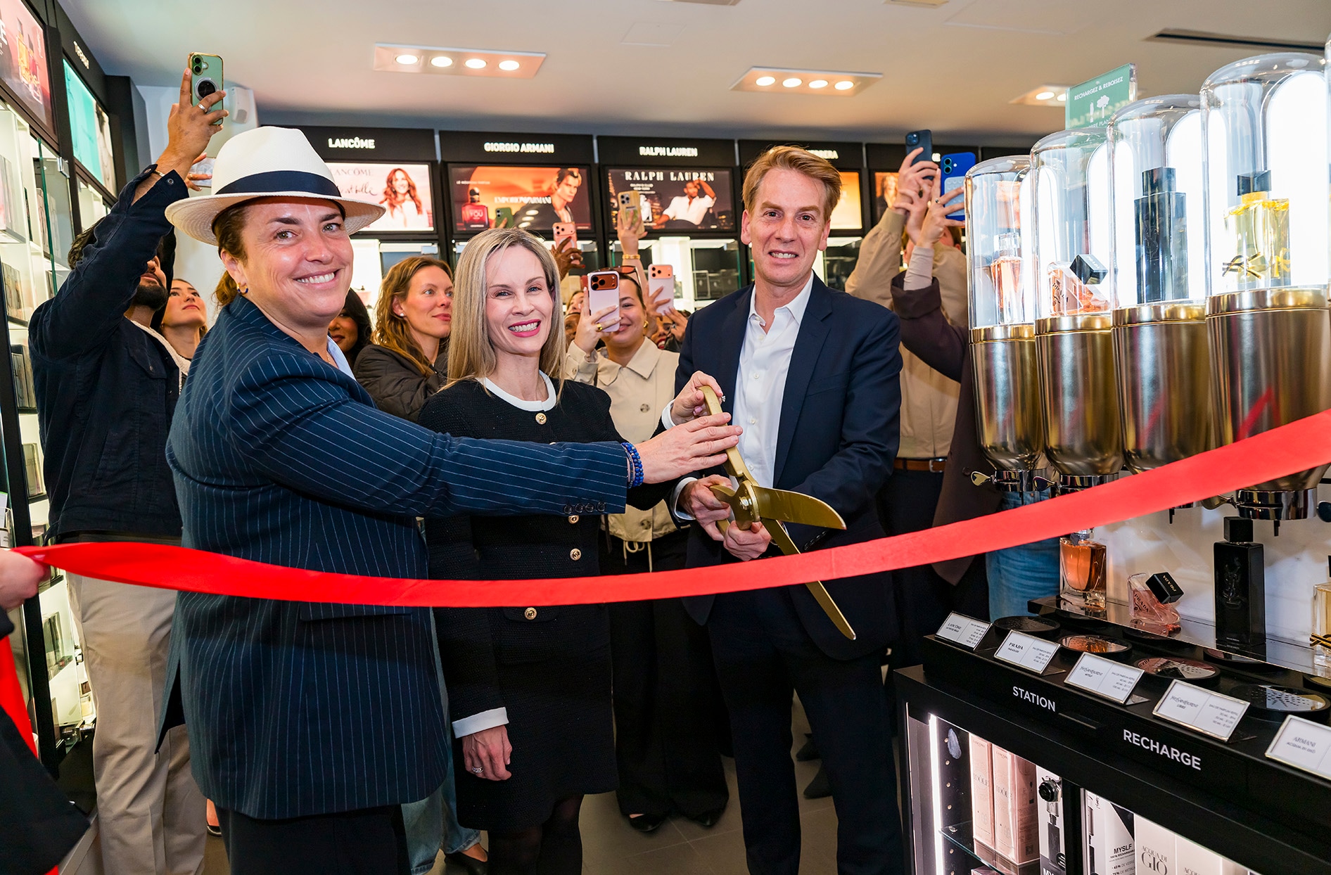 Leith Sinker stands in the middle cutting a red ribbon inside a Shoppers Drug Mart location.