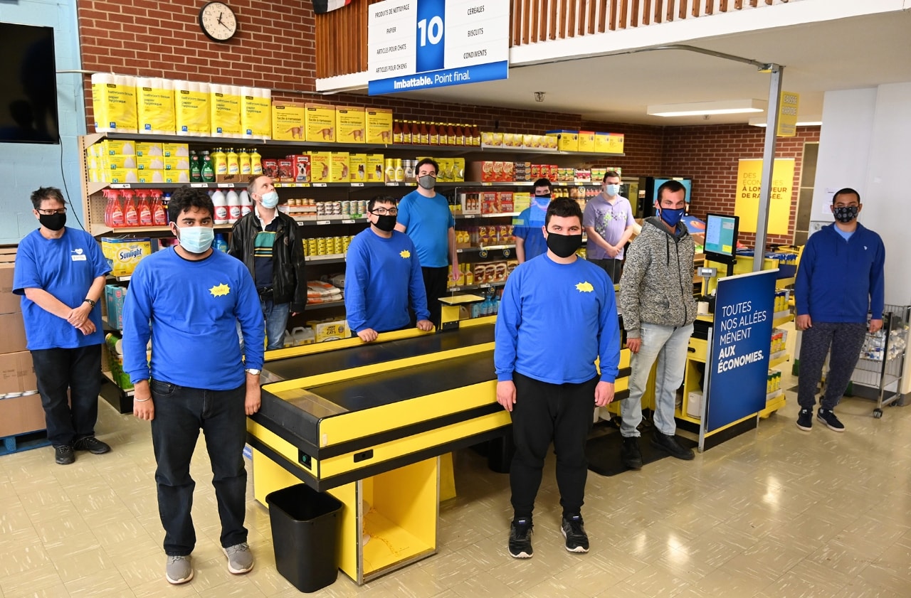 10 des participants se tenant dans une reconstitution d’une mini épicerie