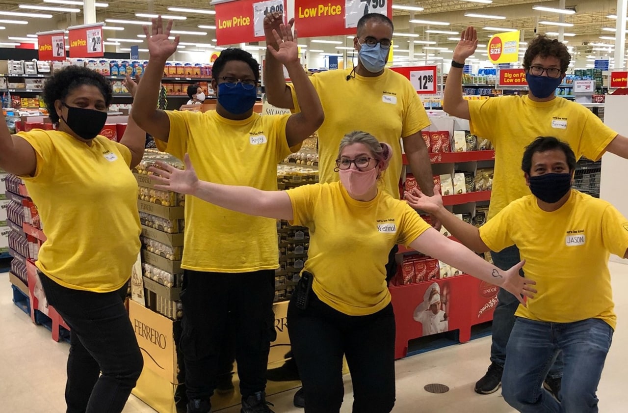 Six colleagues in yellow shirts with their arms up 