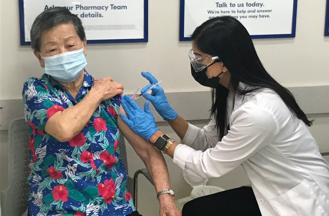 Pharmacist administering vaccine to older person