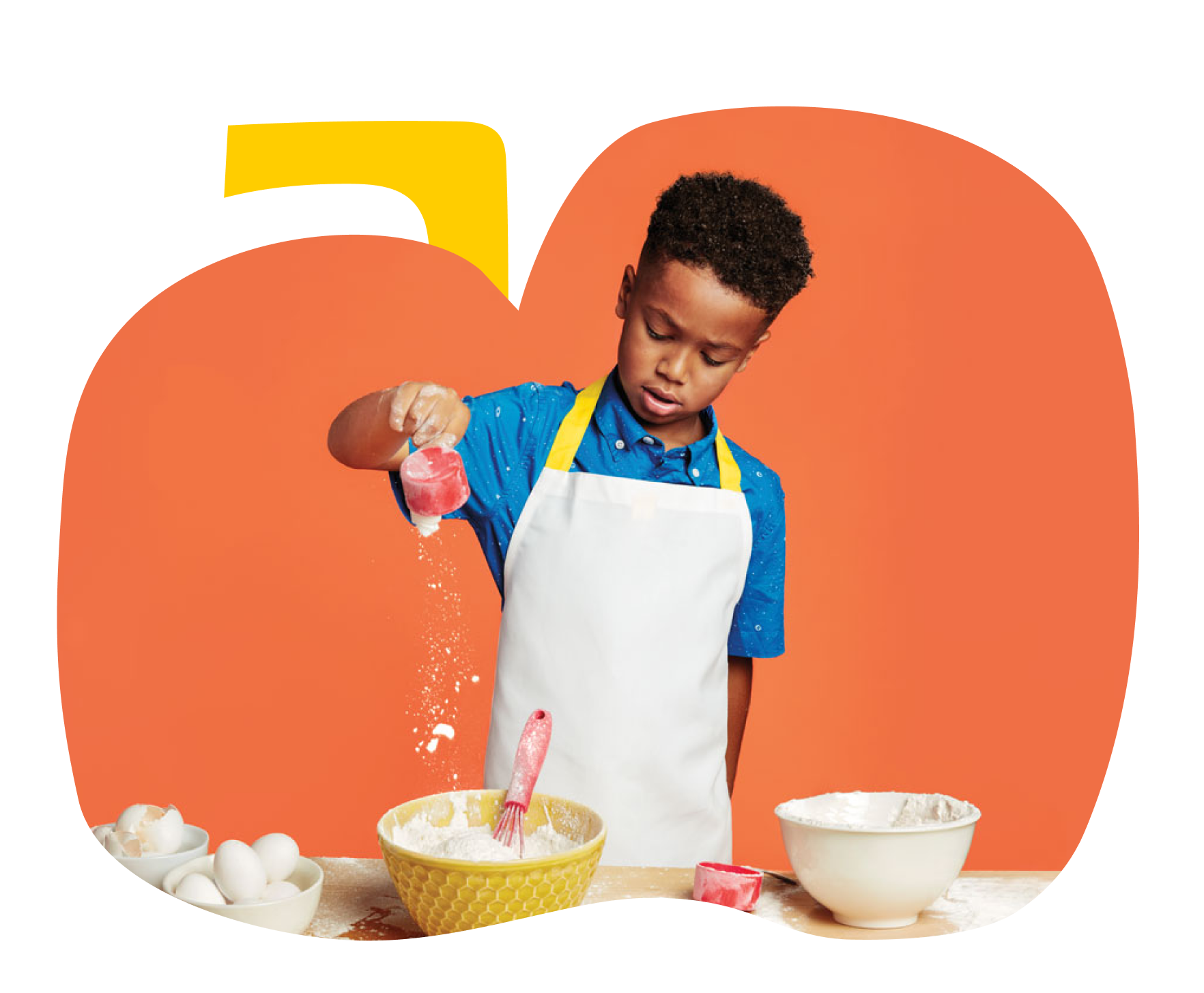 Young boy pouring a cup of flour into a mixing bowl.