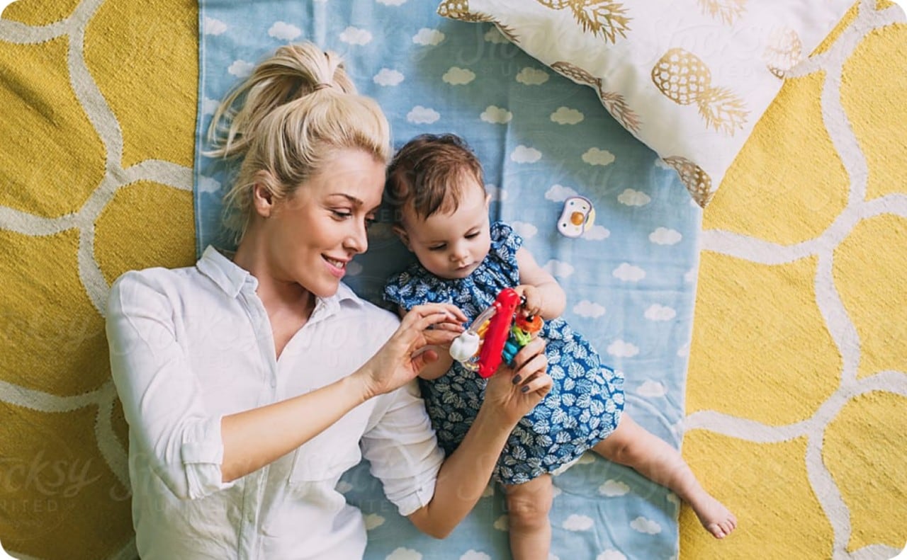 Woman playing with a baby lying down on a blanket