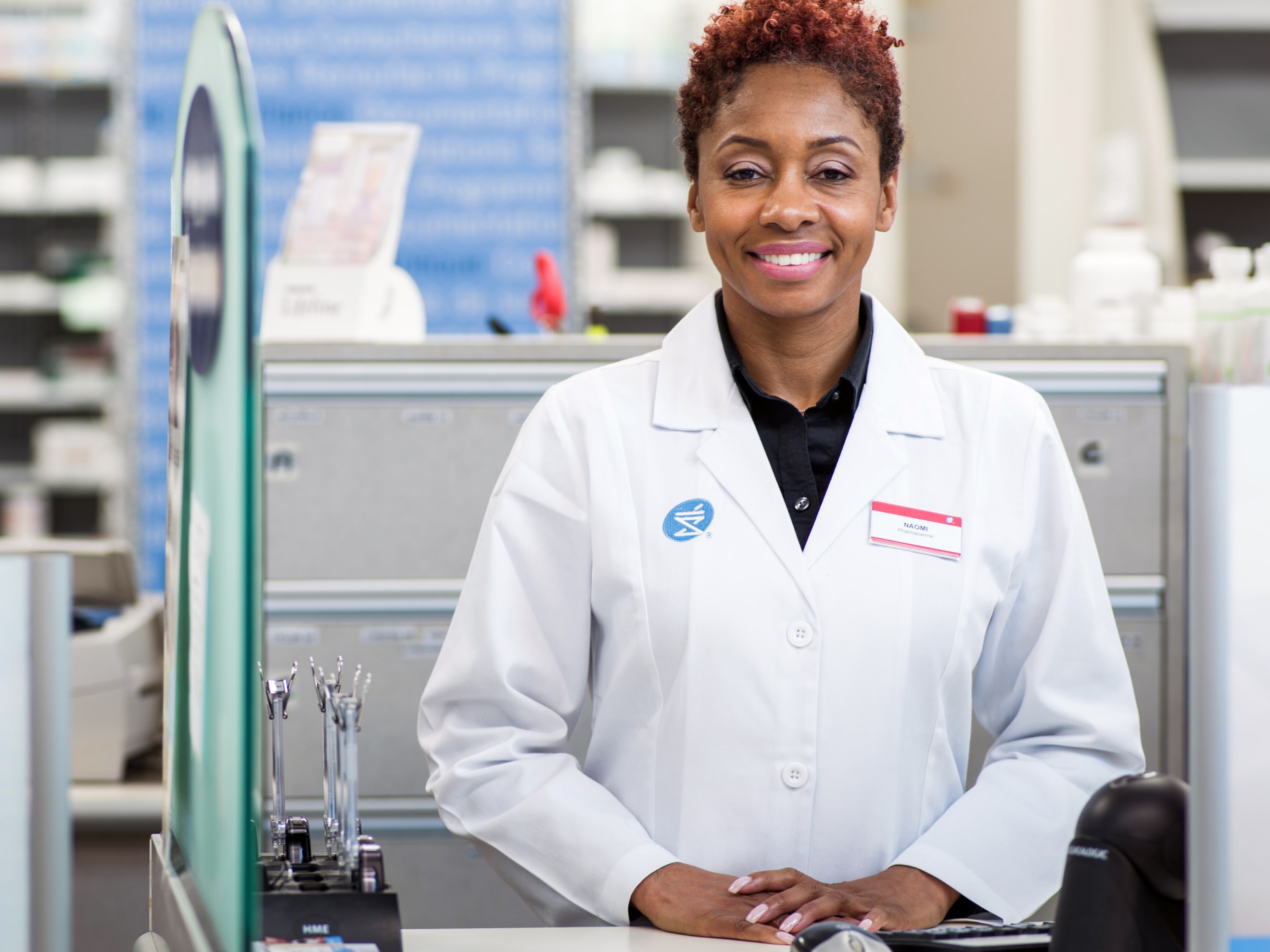 Smiling lady in white pharmacy coat