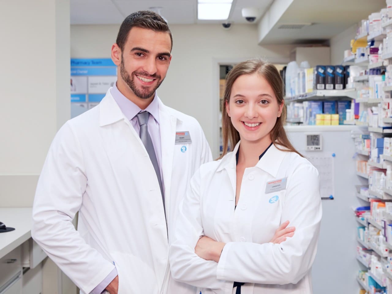 Deux personnes souriantes qui portent des blouses de pharmacie