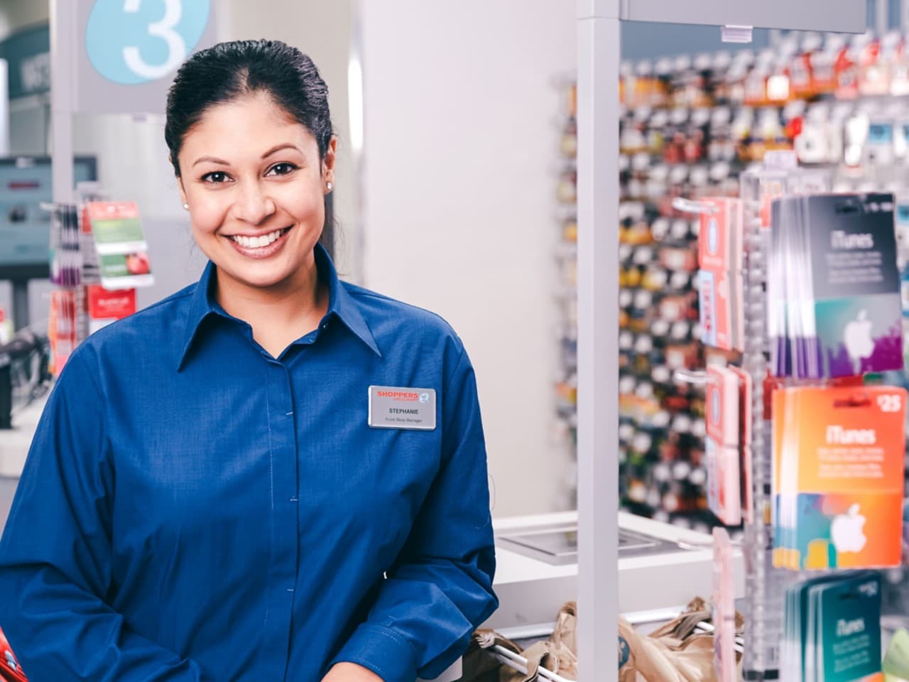 Femme souriante dans un magasin Shoppers Drug Mart, portant une chemise à col bleu